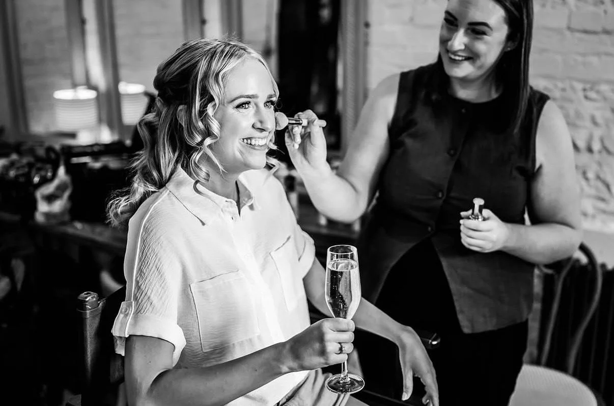 Bridal Hair and Makeup artist giving a bride her final touch ups on her wedding day