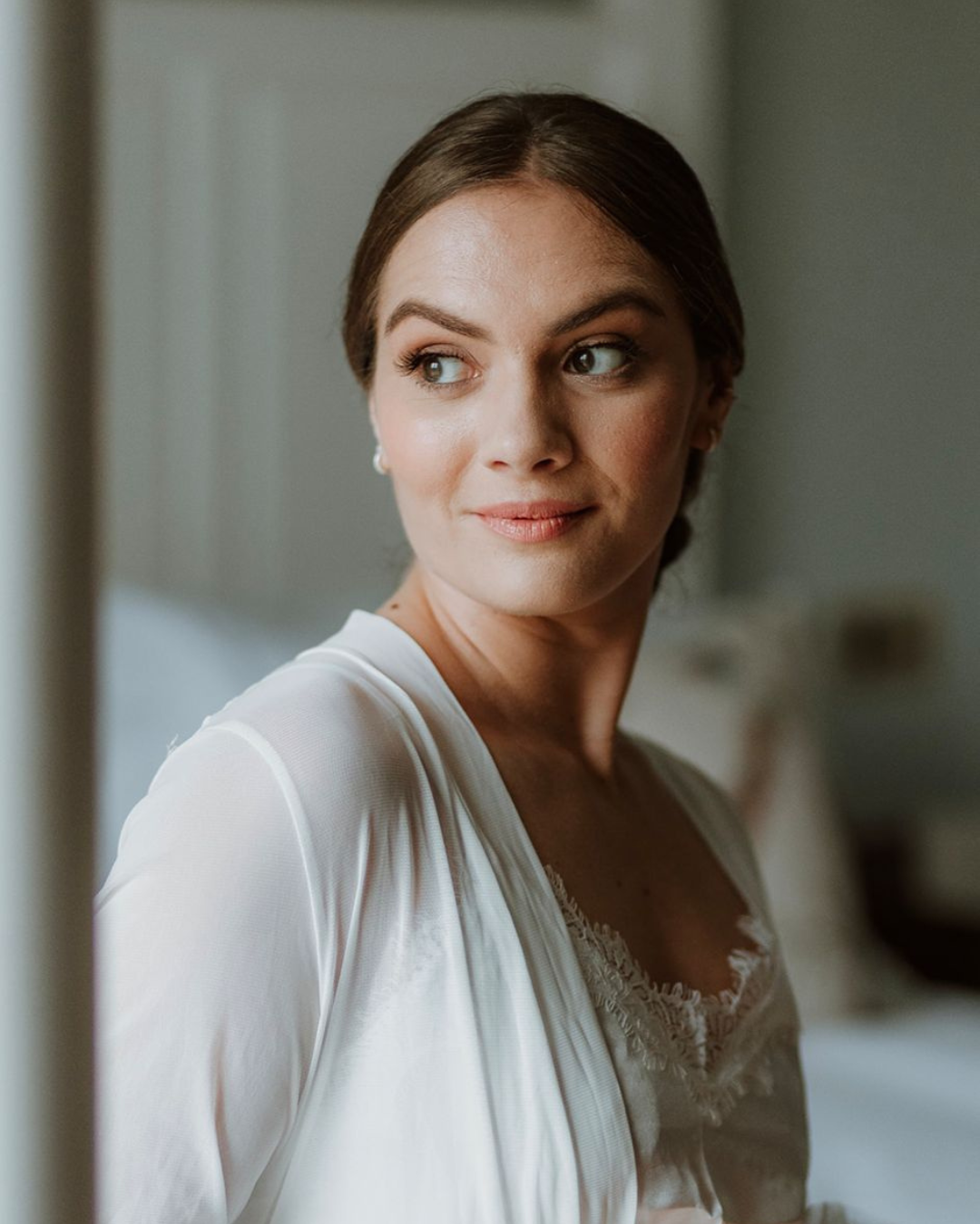Bride looking out of the window with soft natural wedding makeup
