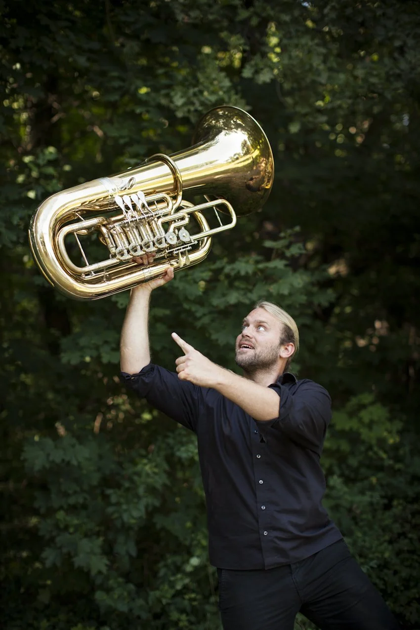 Andreas Martin Hofmeir pitää tuubaa kädessään pään yläpuolella.