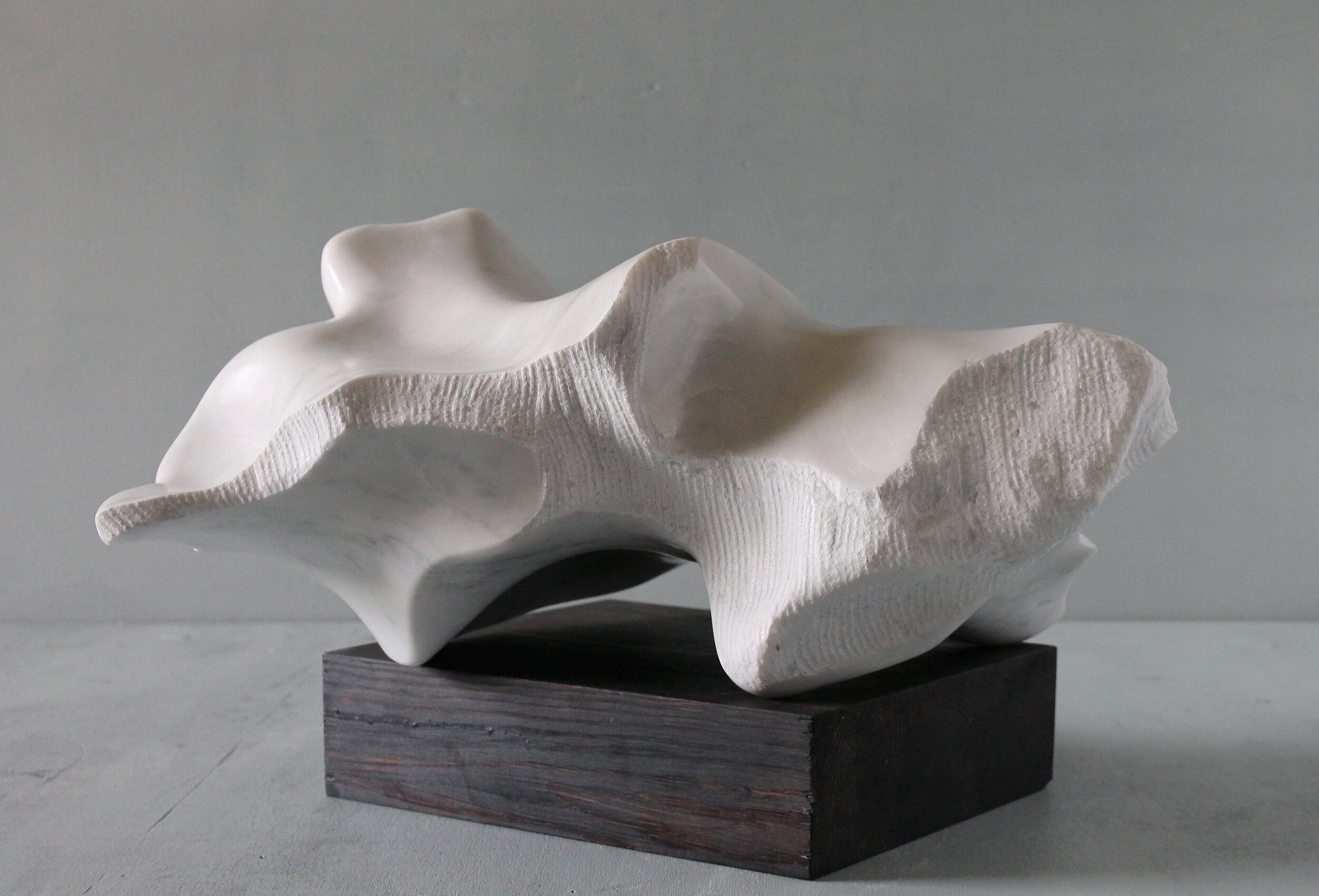 Blowing Through the Stone, 11.8" x 18.11" x 11.8", white Carrara marble on wooden base