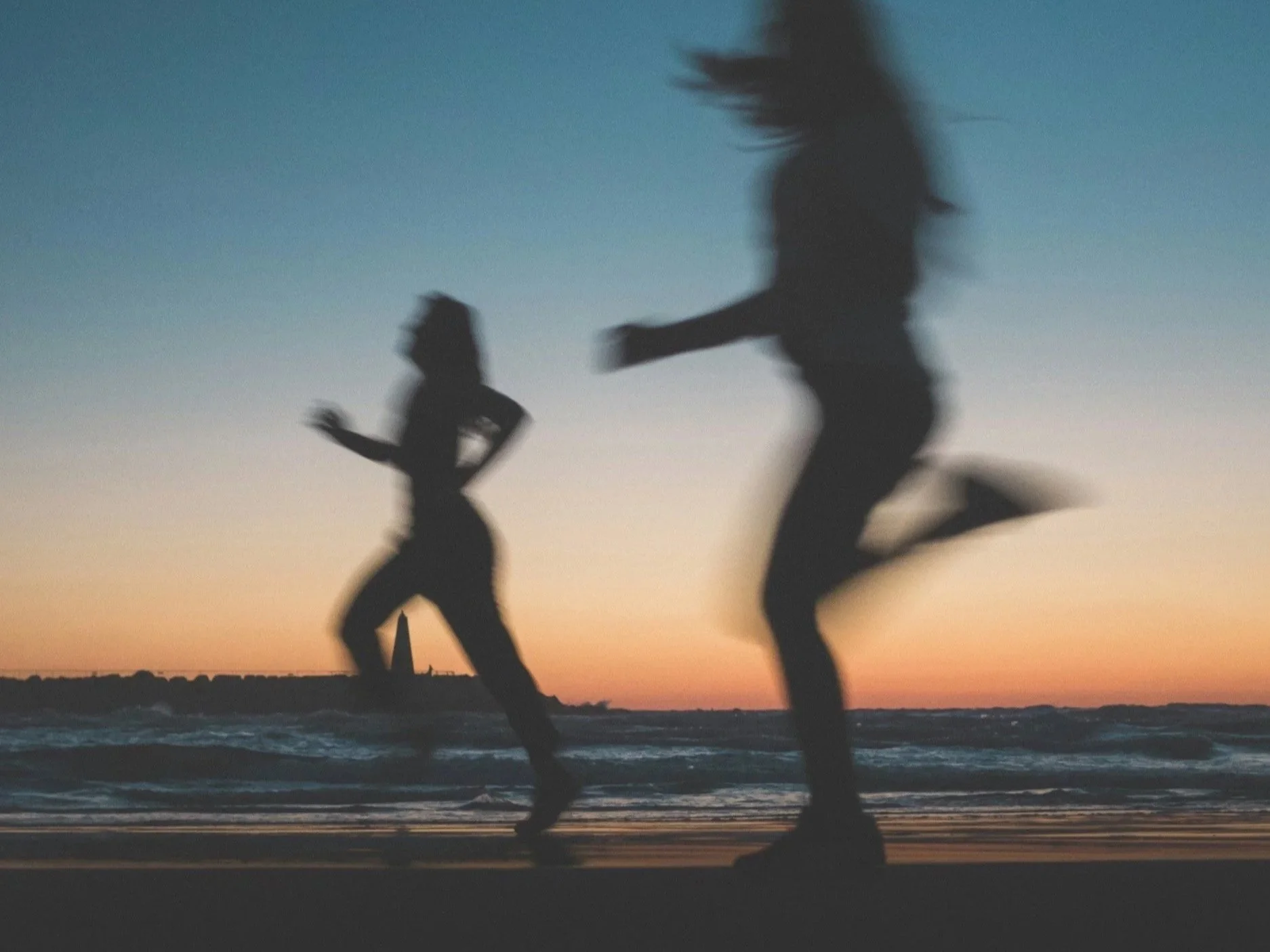 Two silhouettes running vs walking for weight loss on the beach