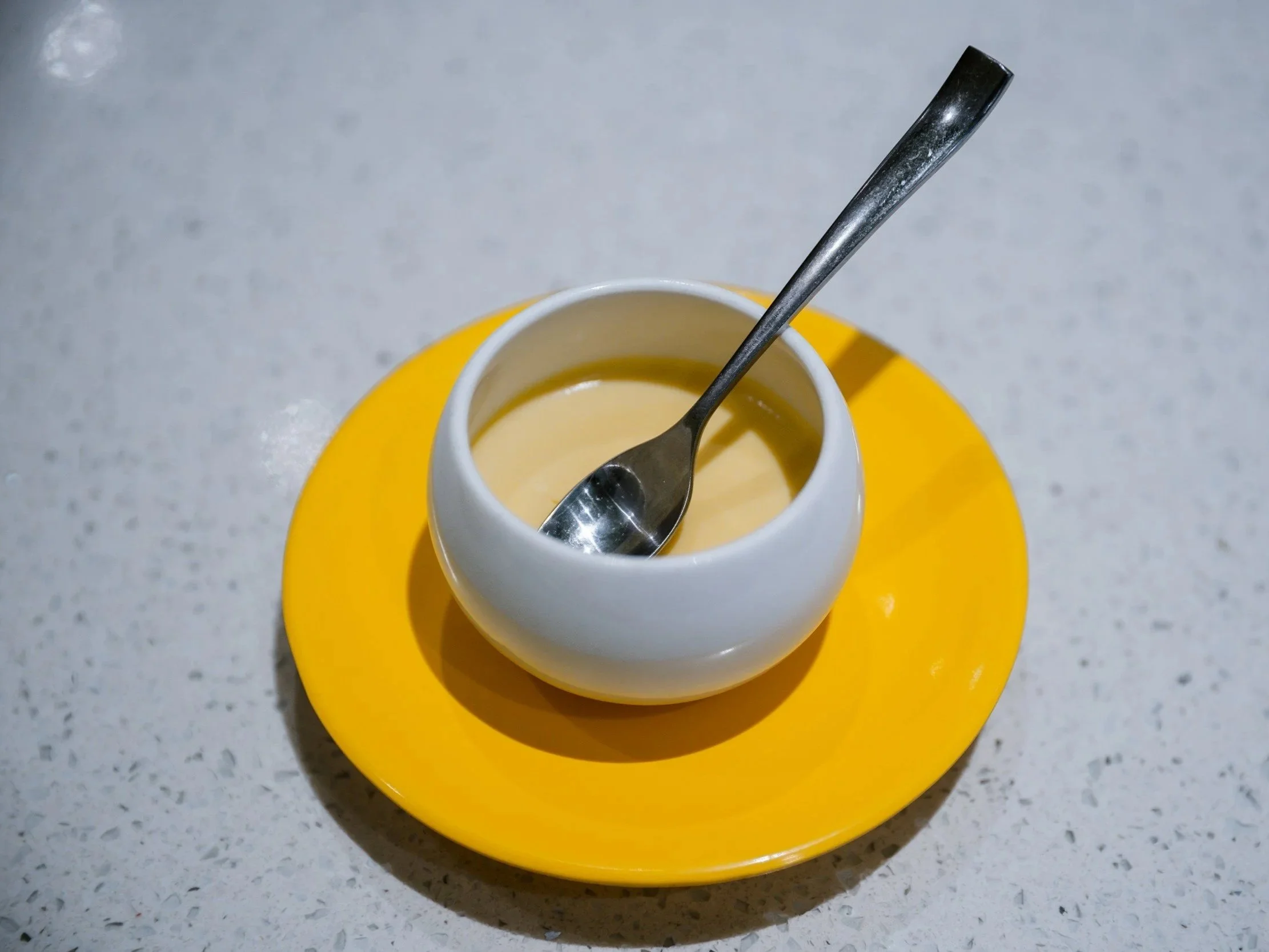 A bowl of honey mustard dressing with a spoon of raw honey
