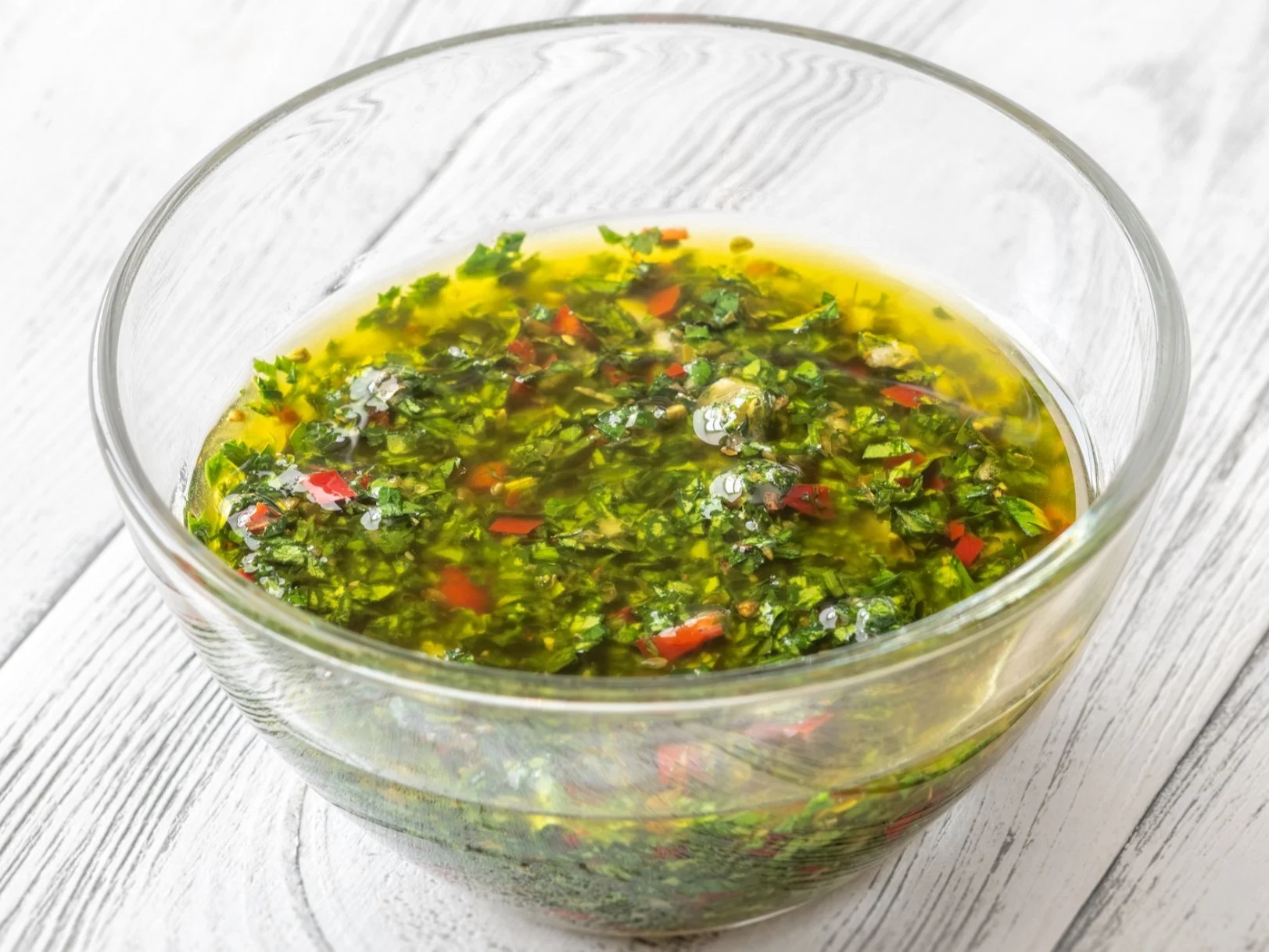 A bowl of chimichurri with fresh parsley and red pepper flakes