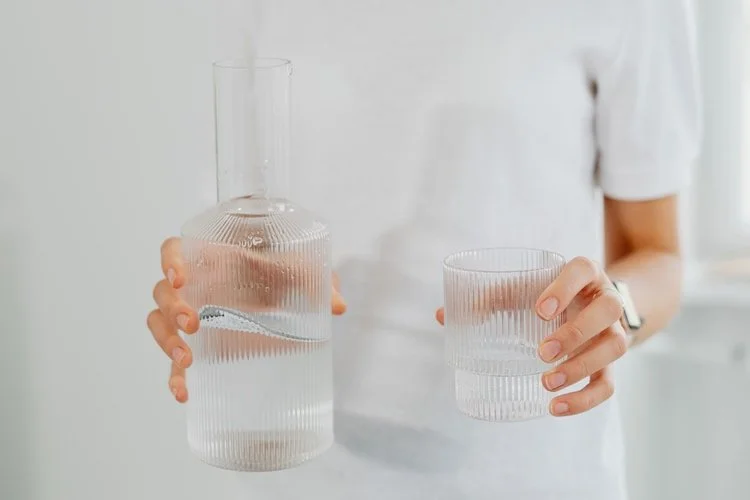 Woman's hands pouring water from a bottle into a glass