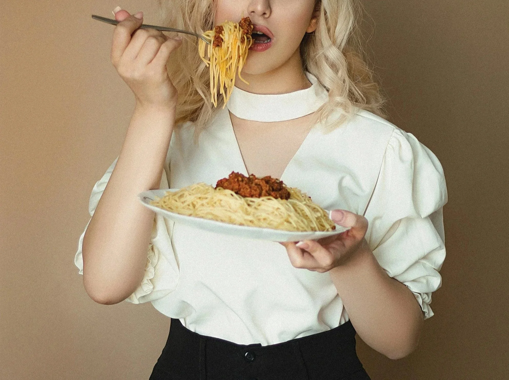 Woman enjoying a bowl of pasta in an editorial fashion shoot