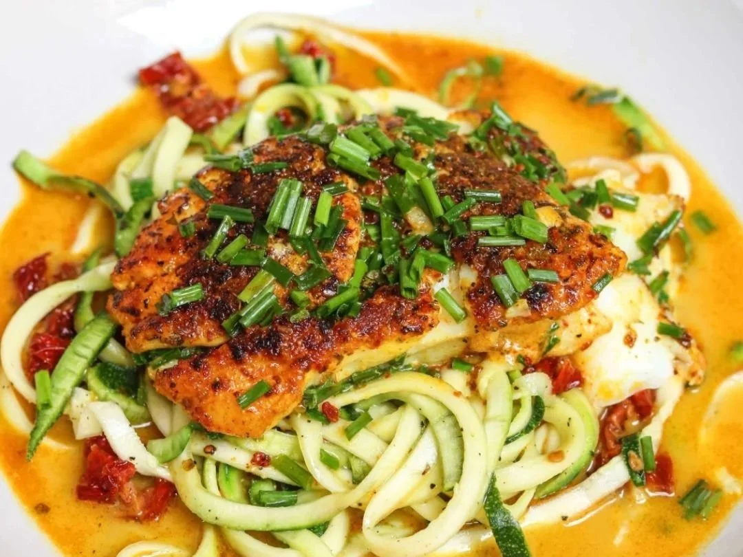 Pan-fried cod in cream sauce over zucchini noodles