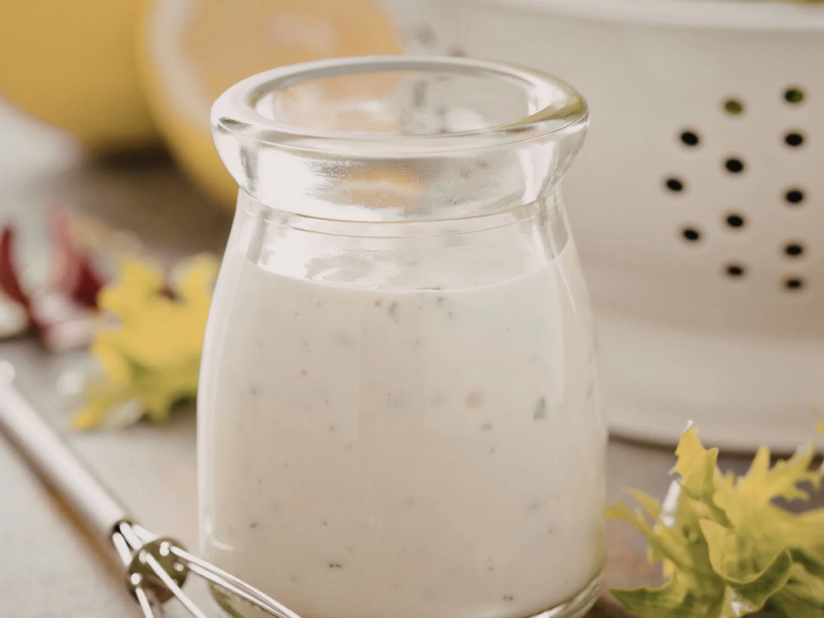 A glass jar of creamy Caesar dressing with parmesan and lemon