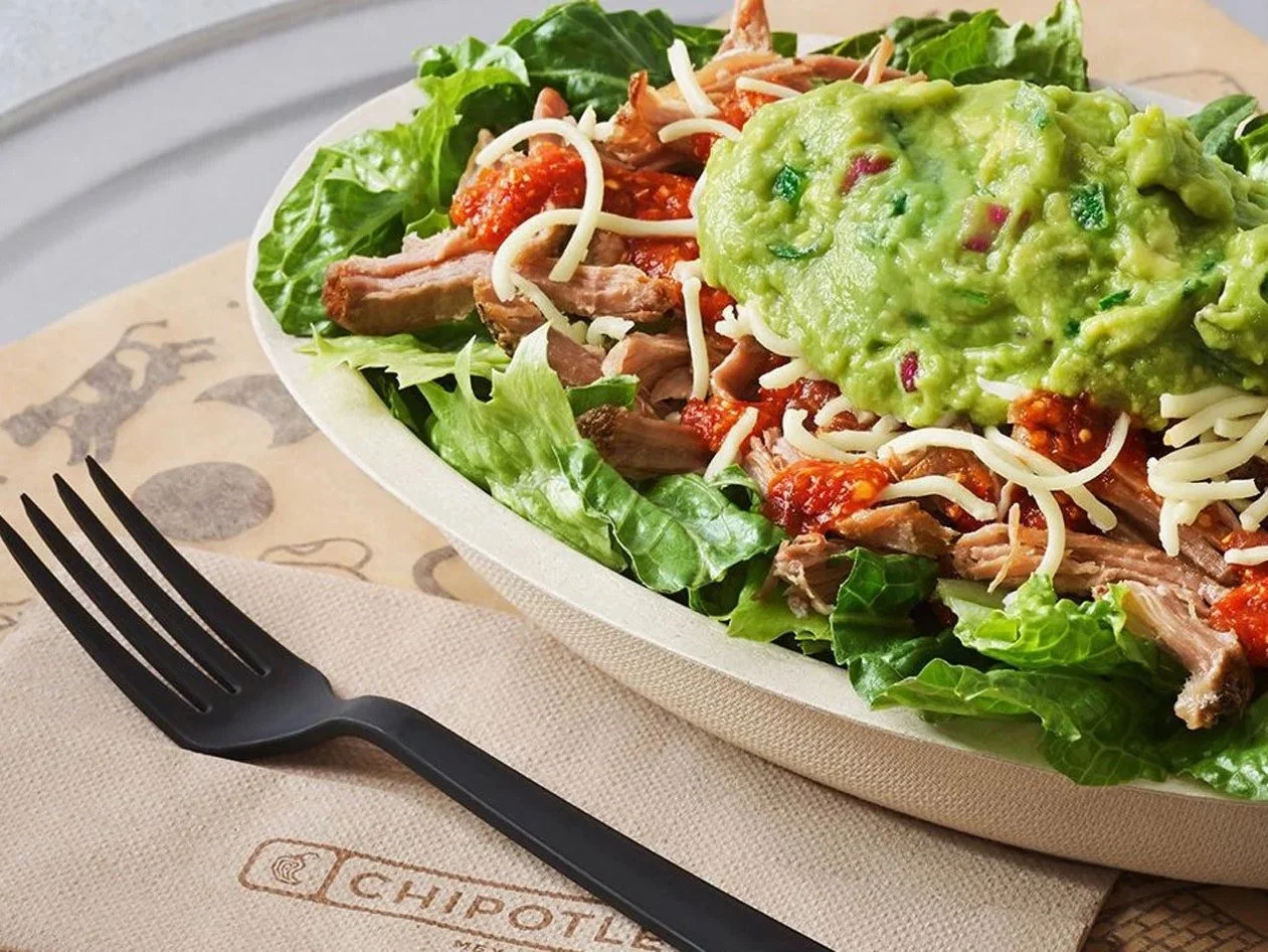 Chipotle protein salad bowl with meat, cheese, salsa and guacamole on greens