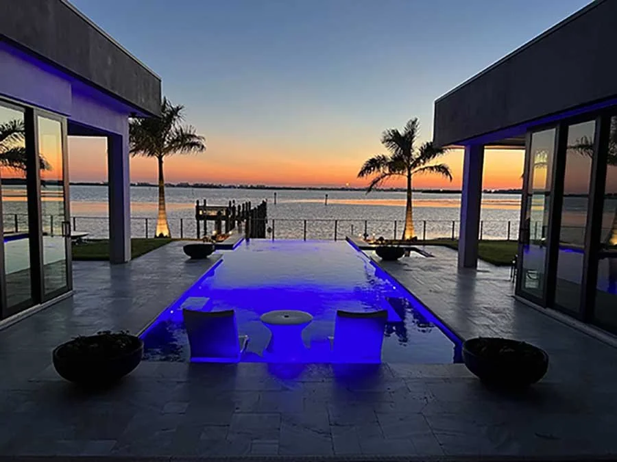 Randy Lee design with modern evening landscape lighting and contemporary patio and pool integrated into contemporary beach front home