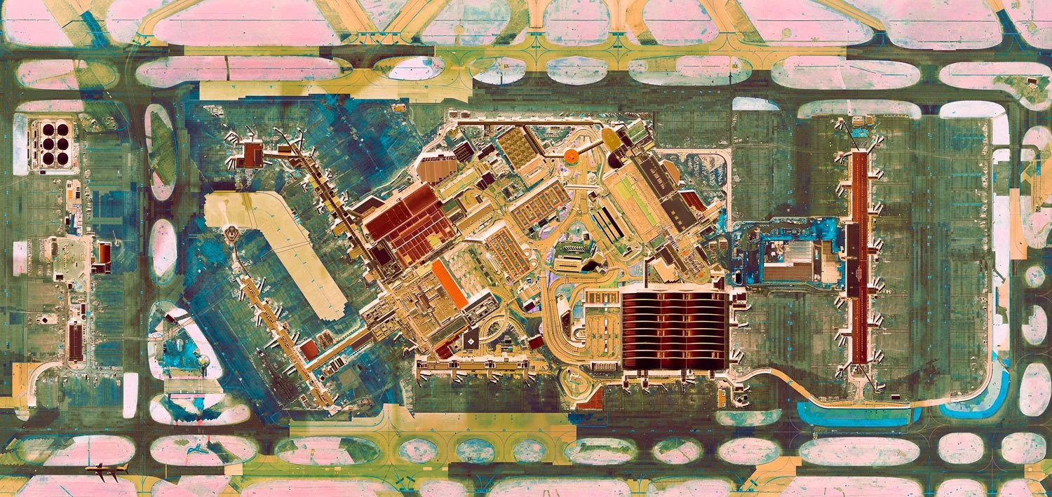 Aerial view of an industrial facility or airport with runways, taxiways, and buildings, viewed from above.