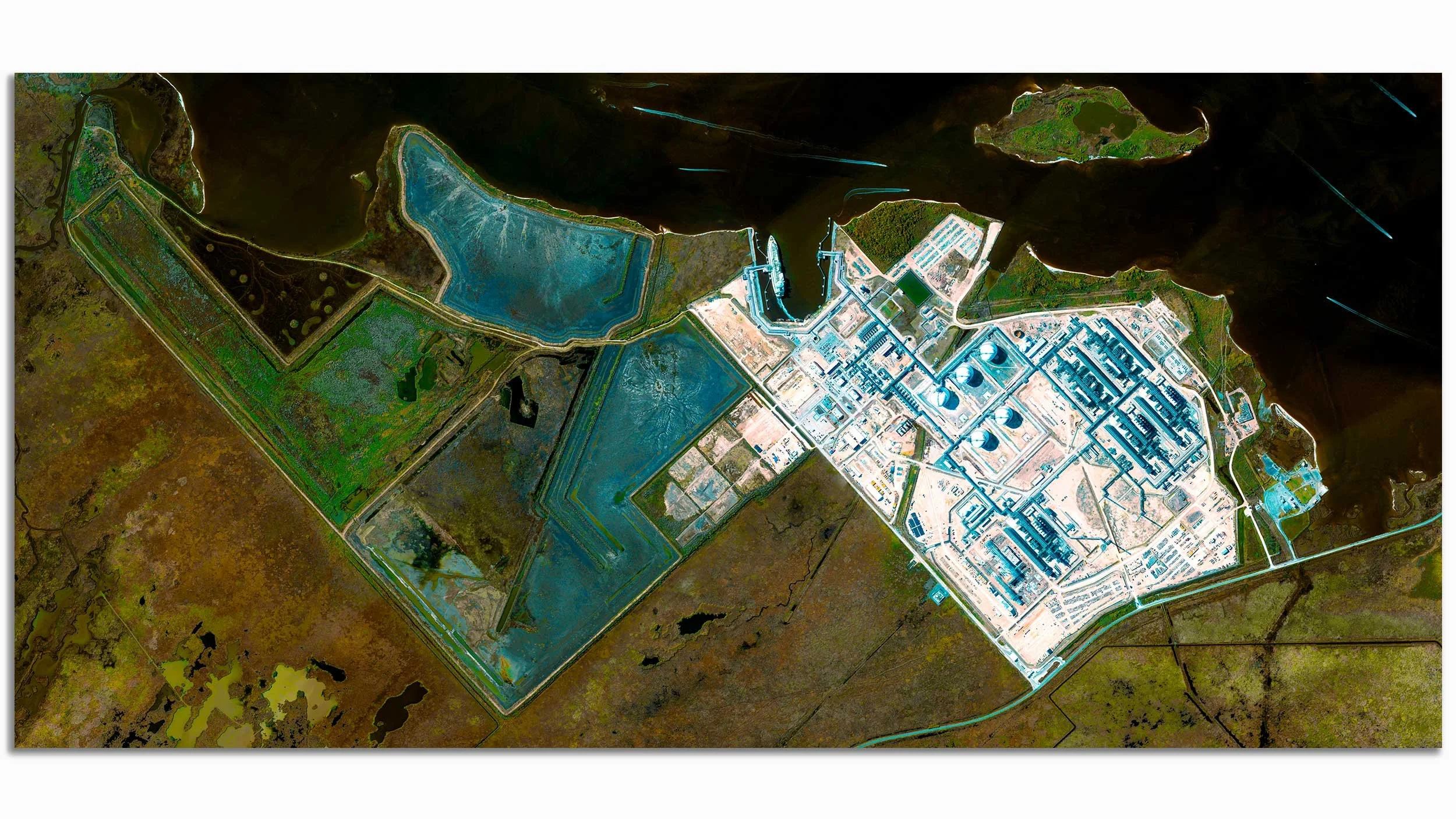 Aerial view of a water treatment plant with large tanks, pipes, and buildings, surrounded by wetlands and green areas.