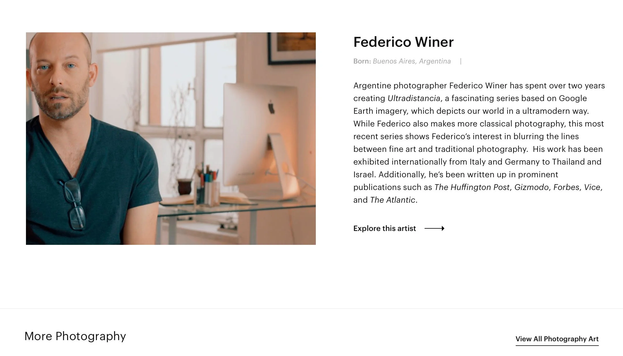 Photograph of Federico Winer, a man with a beard and blue eyes, wearing a dark t-shirt, sitting in a well-lit room with large windows, a desk, and a white computer monitor in the background.