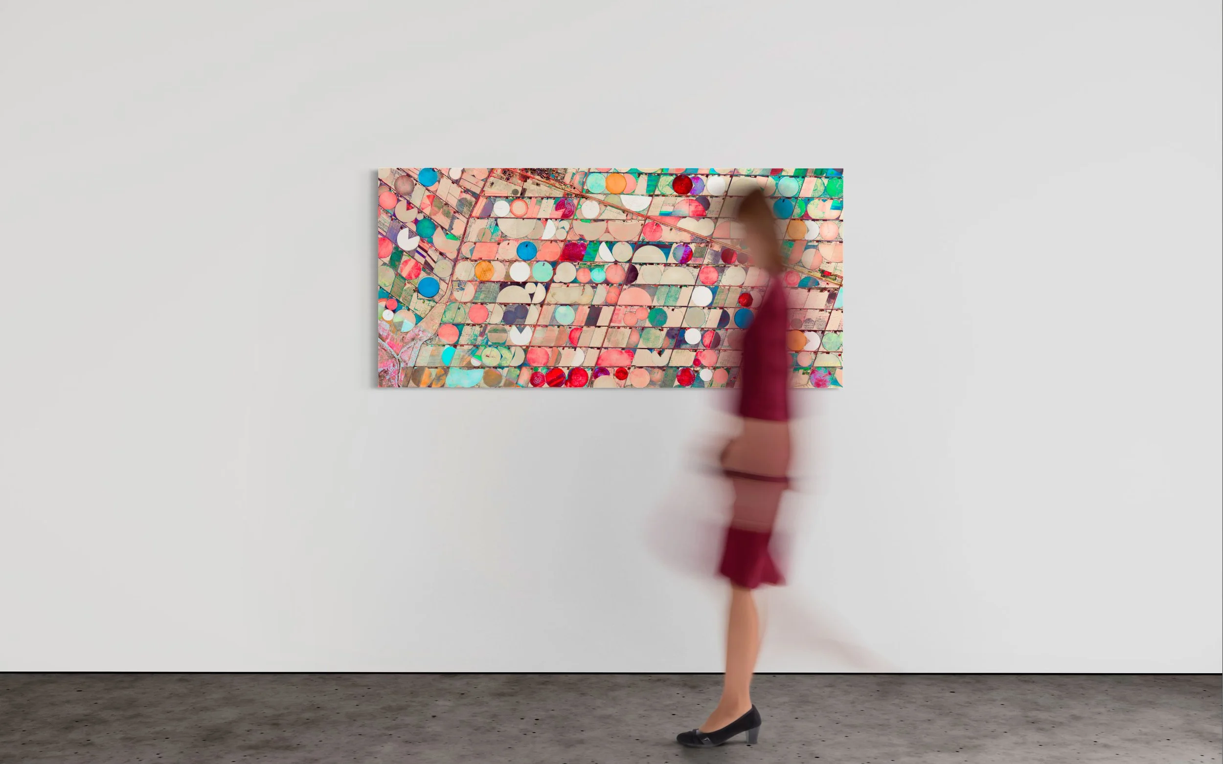 Museum-style view of Ultradistancia Hartswater by Federico Winer with a blurred figure walking past the artwork, emphasizing its panoramic scale and colorful circular agricultural patterns.
