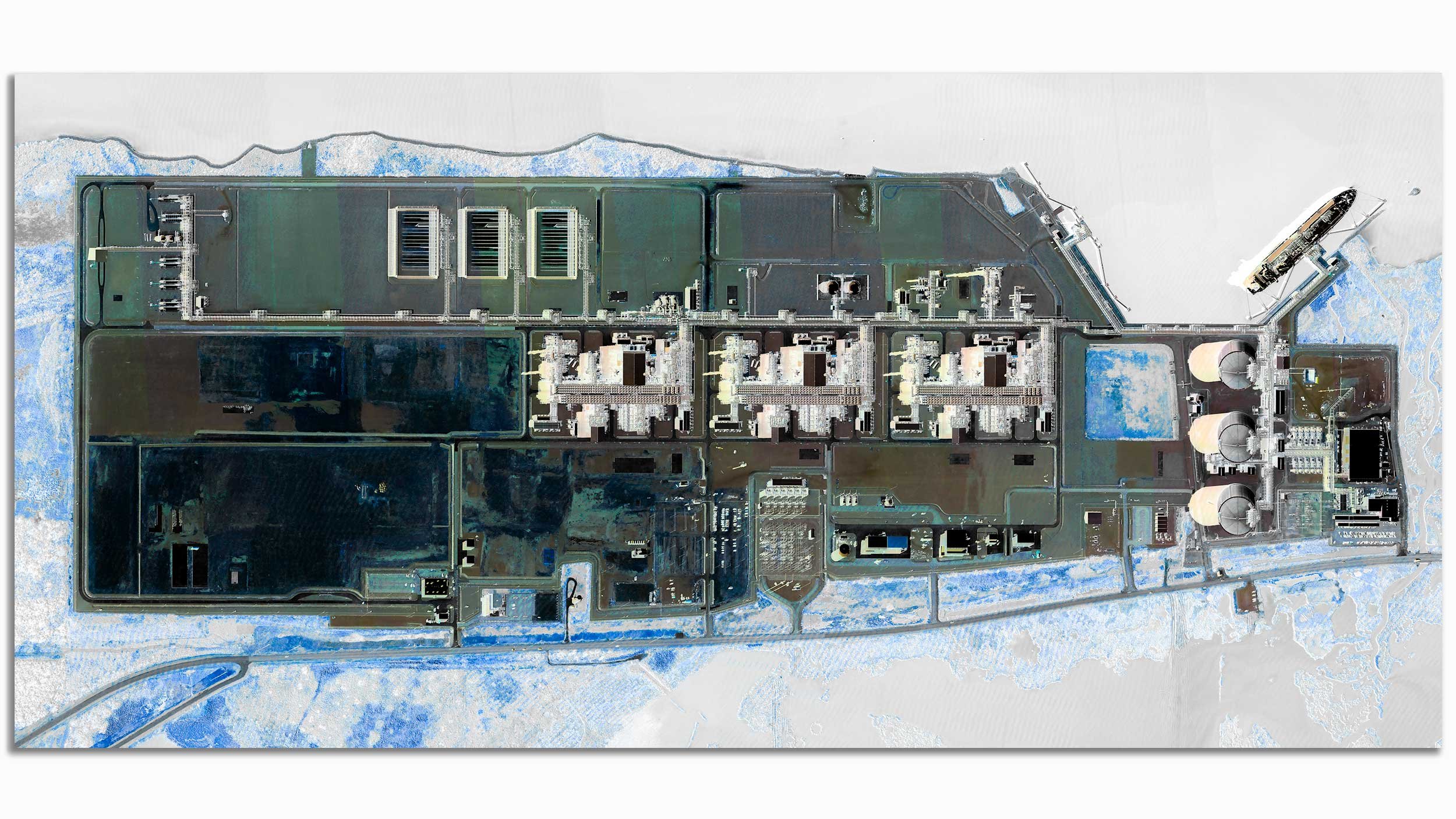A satellite or aerial view of a large industrial or utility facility with multiple buildings, structures, and cooling towers, surrounded by snow-covered land and some water bodies.