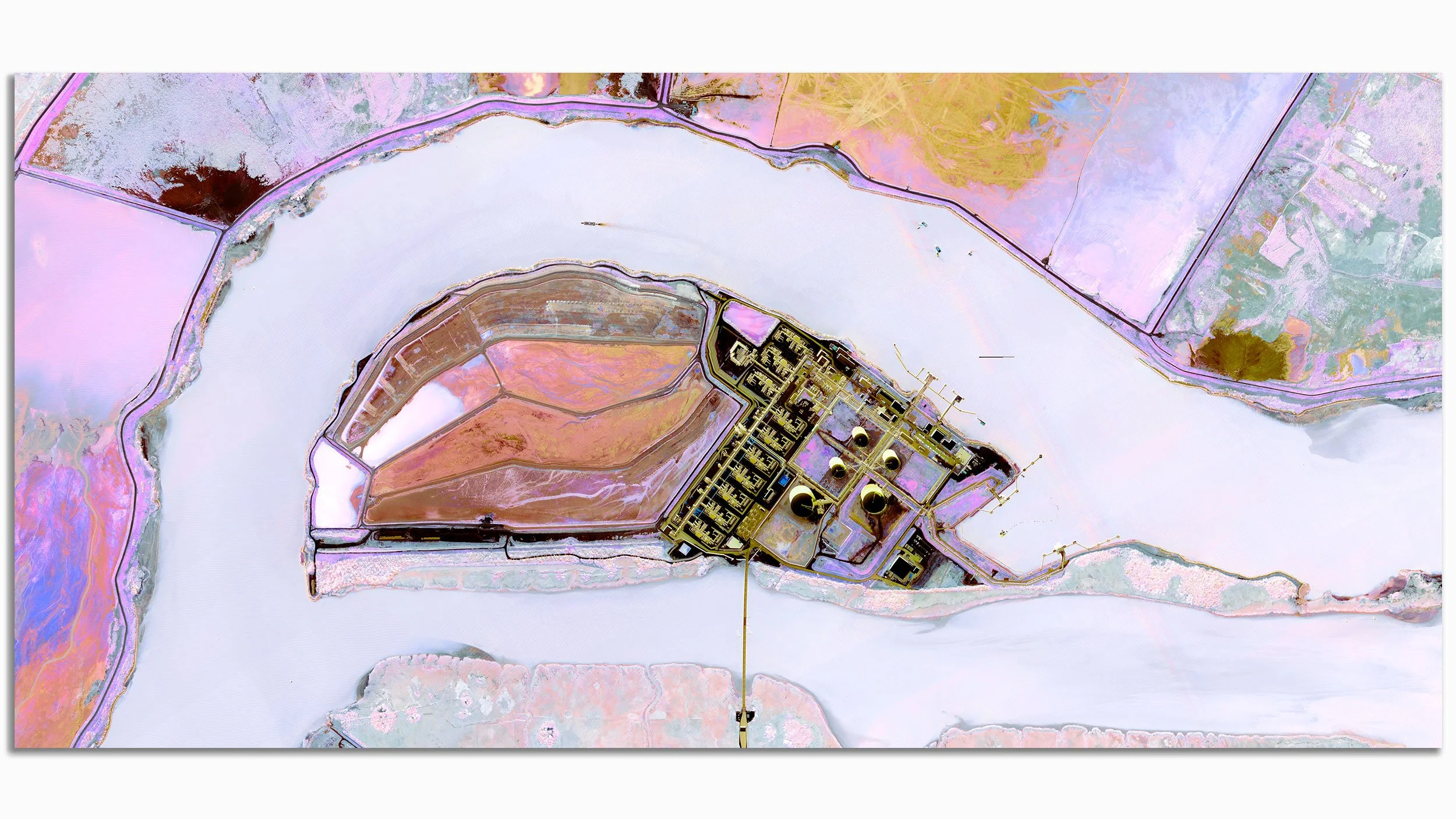 Colorful satellite image of a body of water with surrounding land, including an industrial facility with storage tanks and infrastructure.