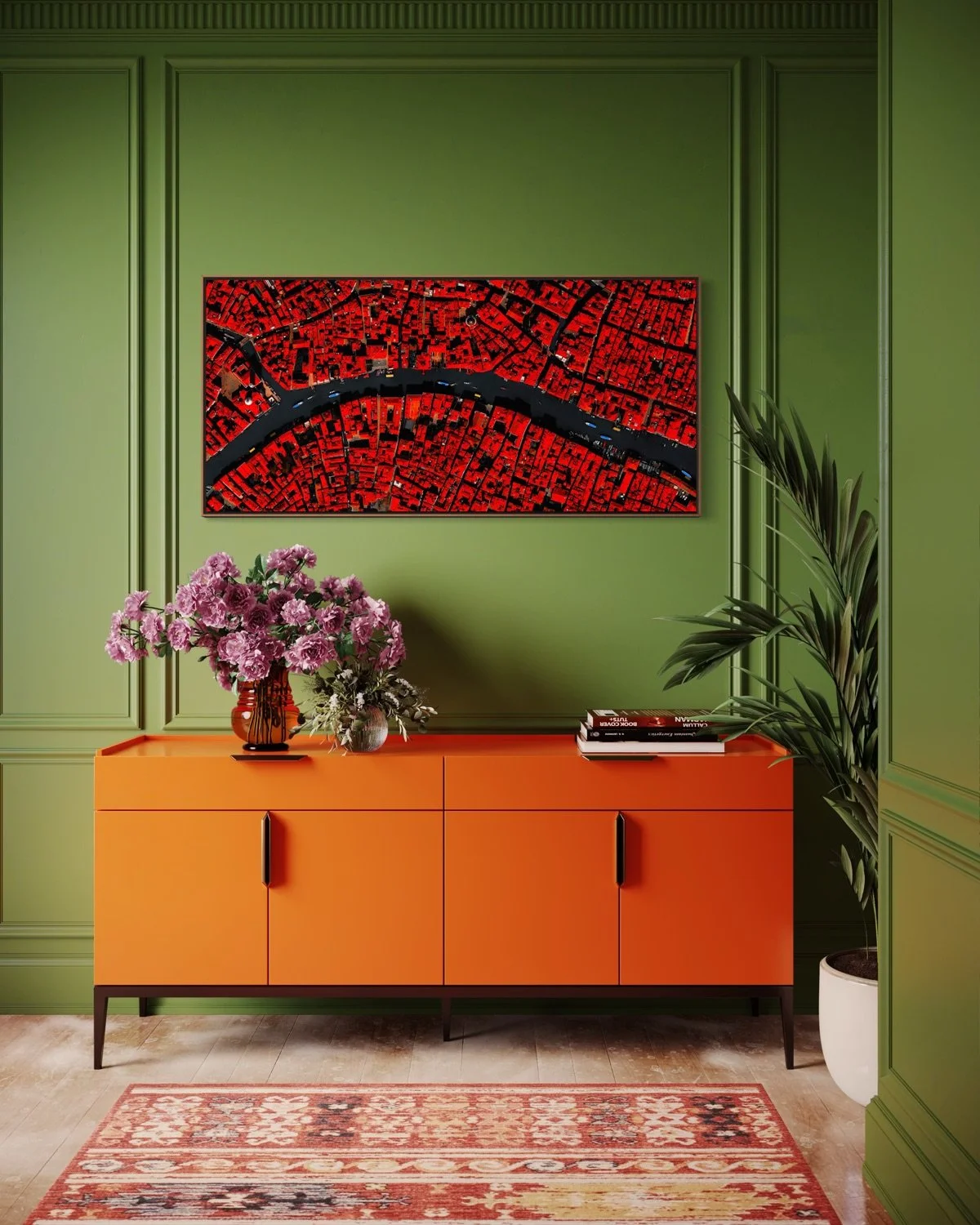 Interior with a green wall, a modern orange cabinet with black handles, a colorful rug, a large floral arrangement, a stack of books, a potted plant, and a framed aerial photograph of a city with a river.
