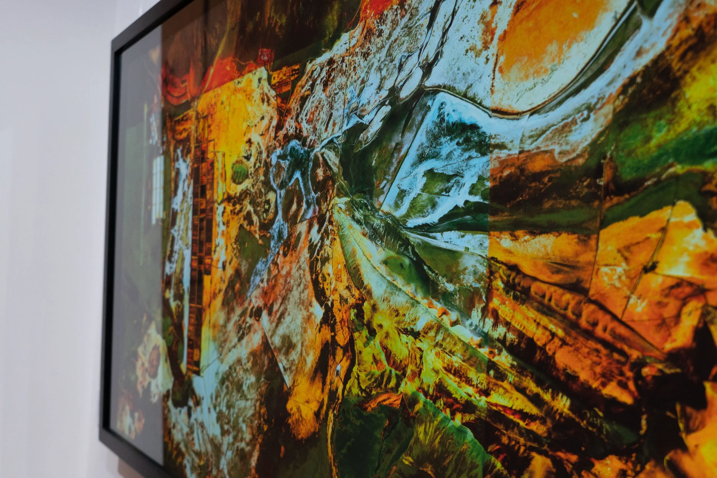A vibrant abstract painting with vivid colors including orange, yellow, green, and blue, displayed on a flat-screen monitor.