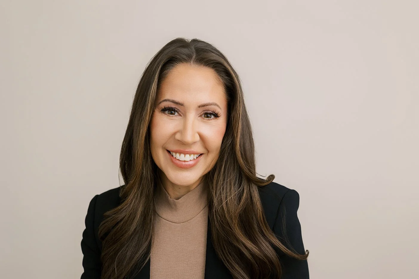 Horizontal image of woman with dark hair and brown eyes being photographed on seamless paper for headshot