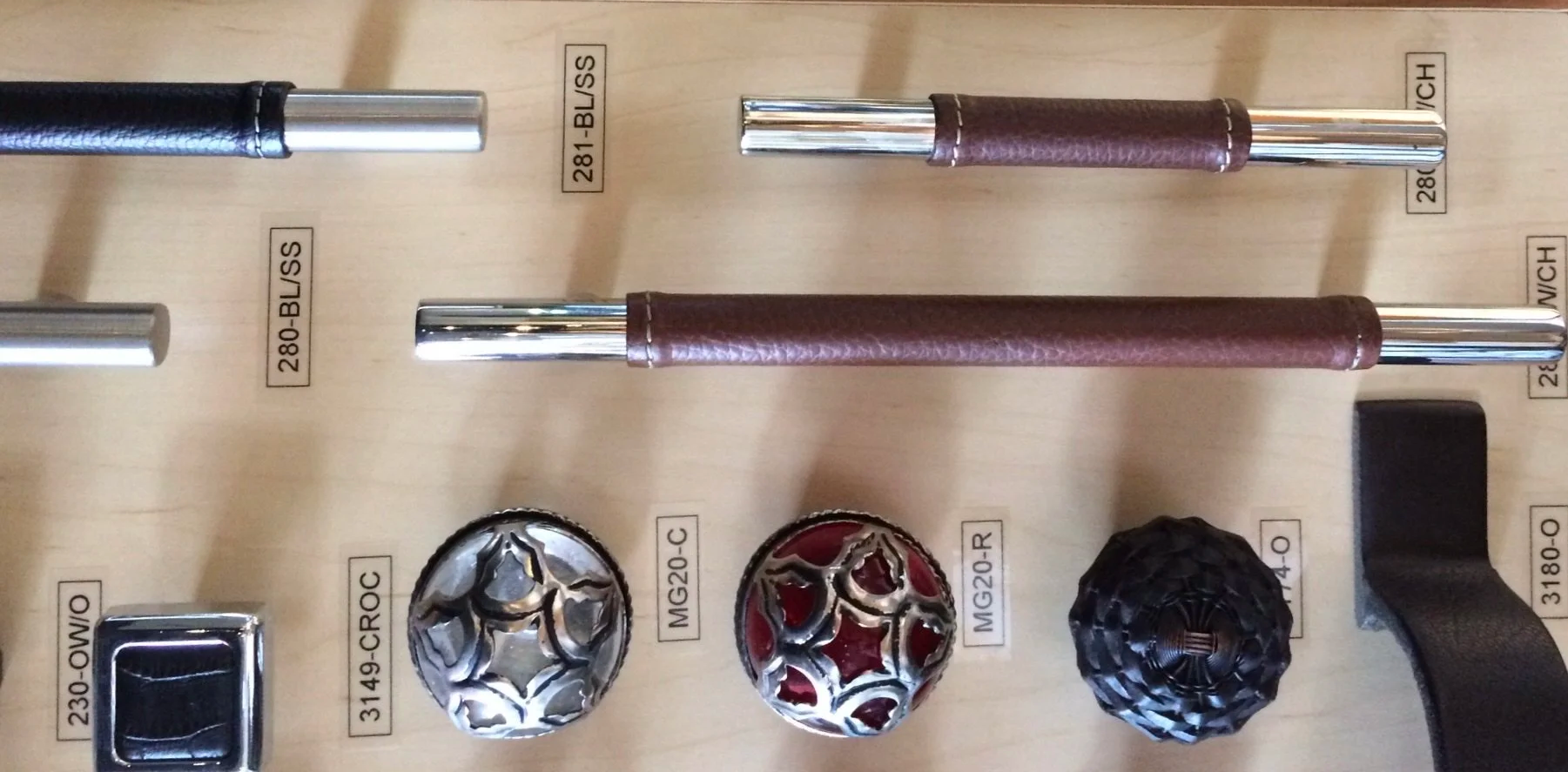 Display of various cabinet hardware and decorative knobs, arranged on a wooden surface.