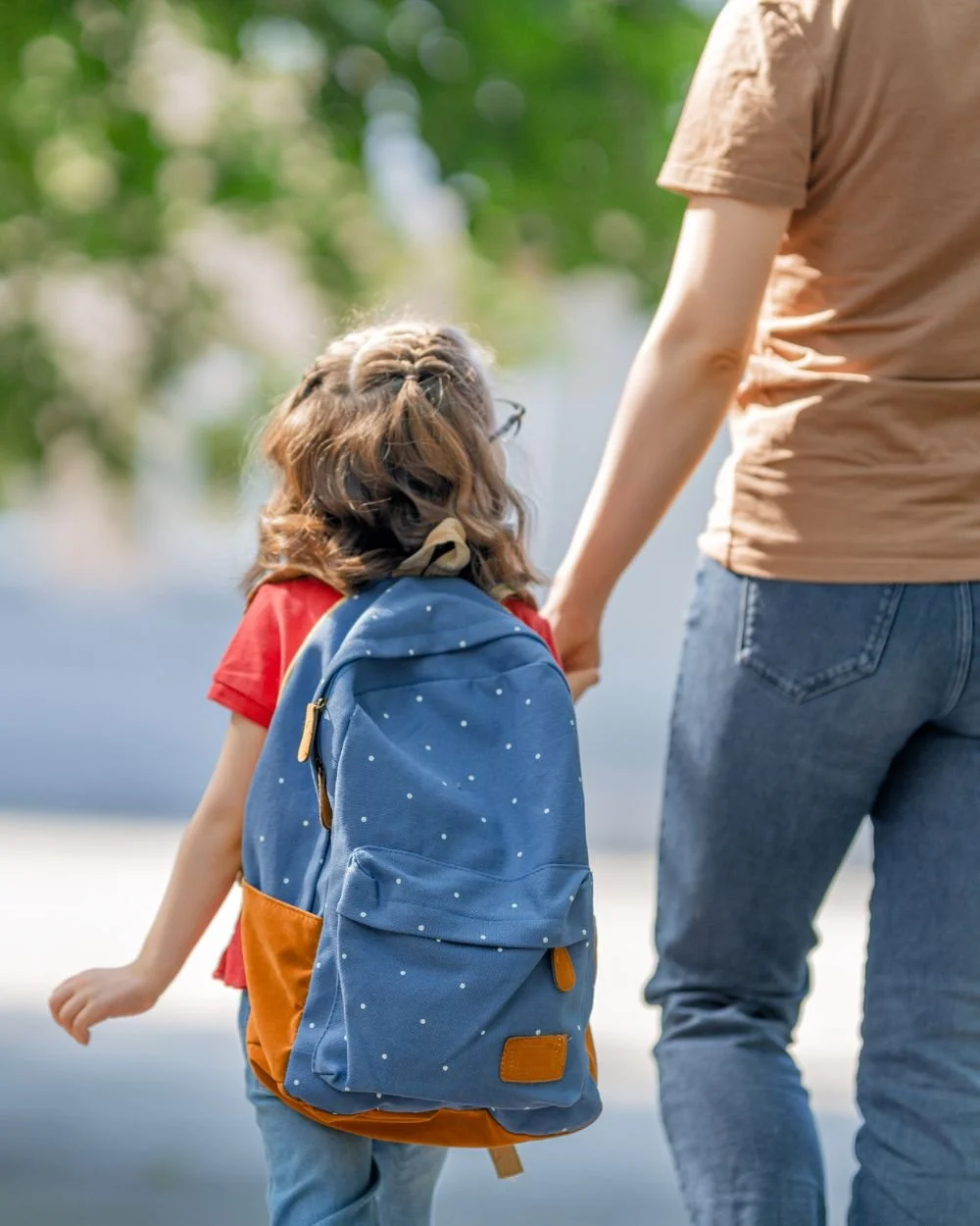 Parent holding their child's hand on the way to school