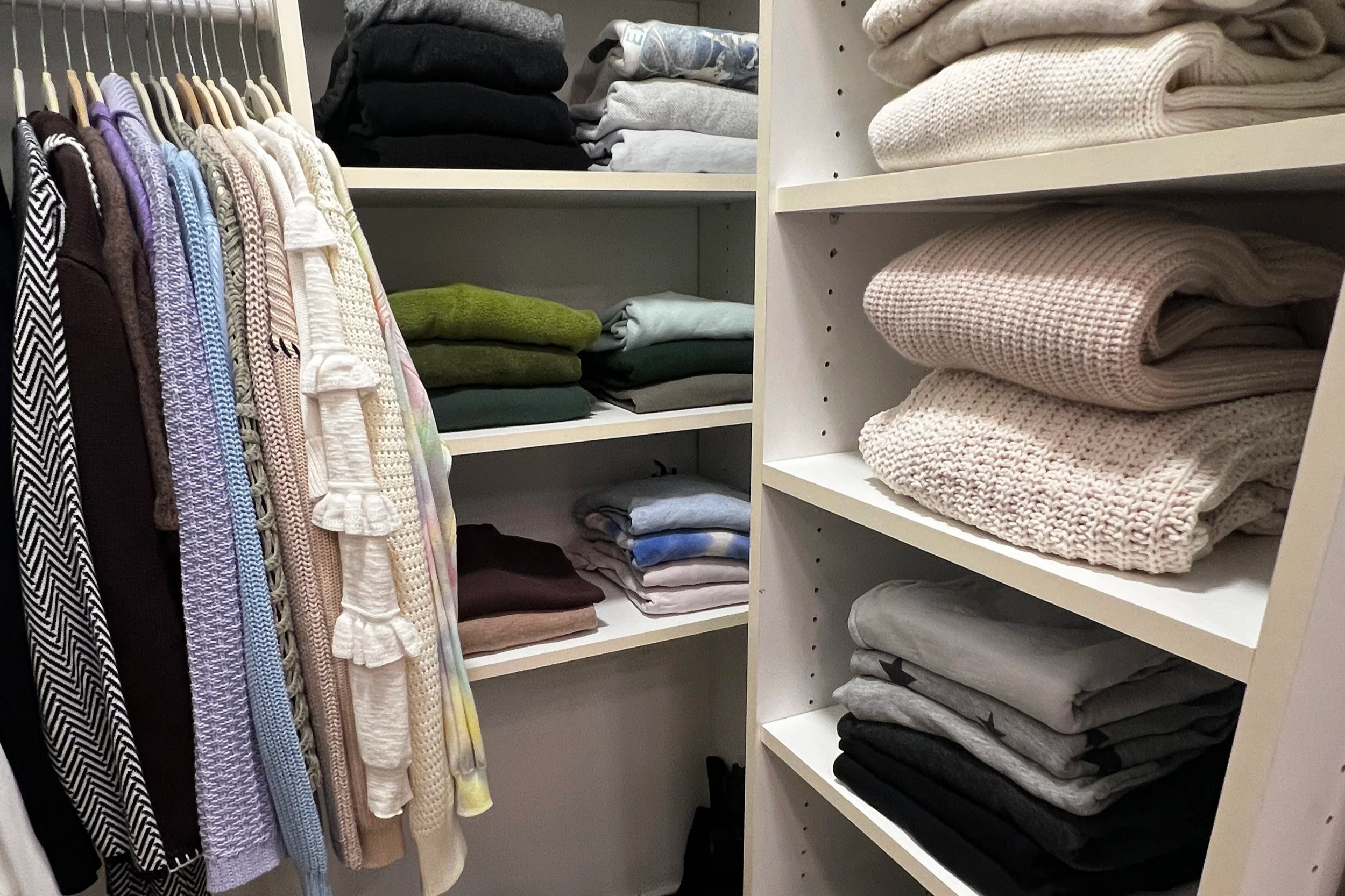Sweaters folded neatly in a walk-in closet.
