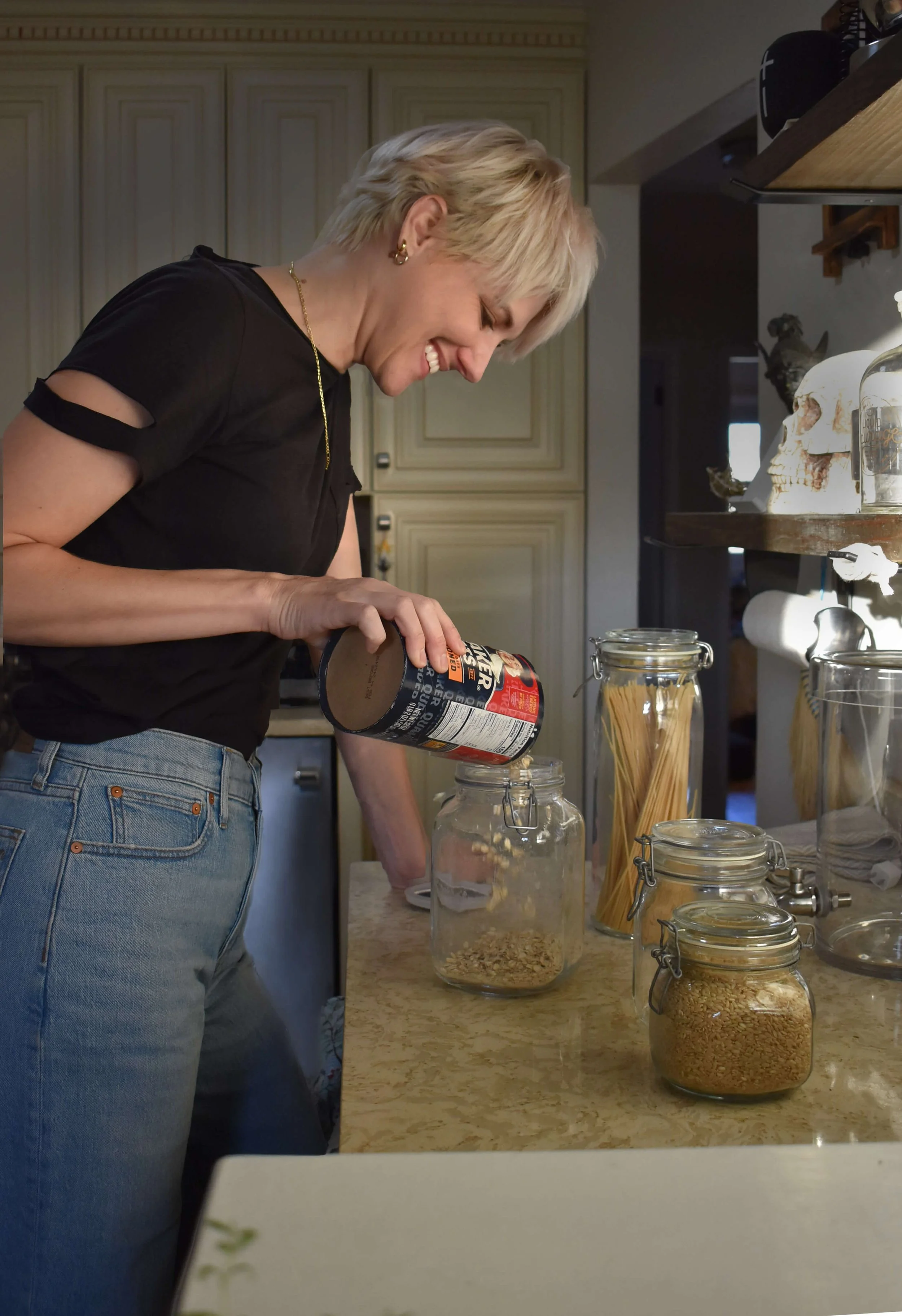A woman smiling while organizing pantry goods.
