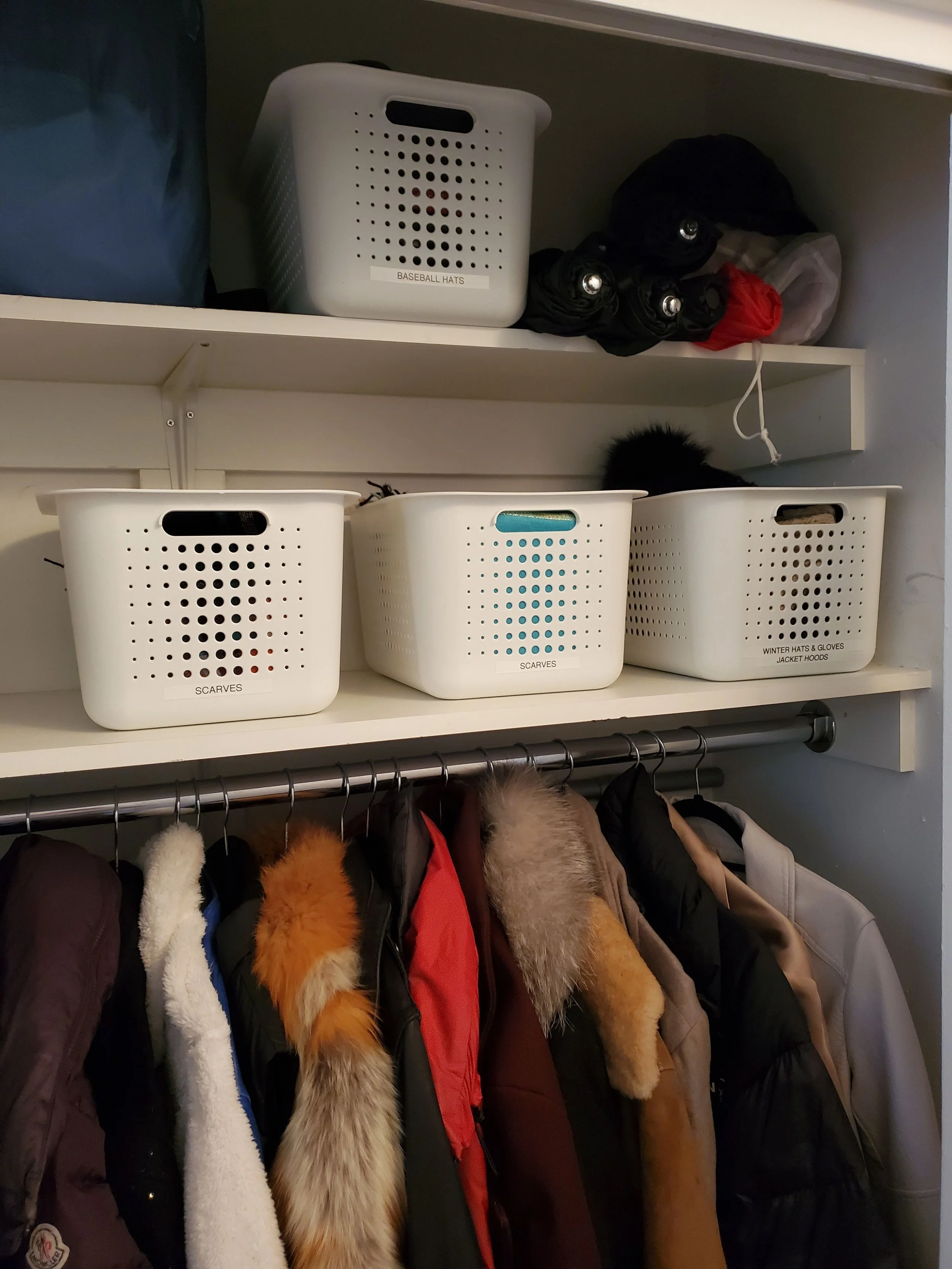 Closet with jackets hung and white bins sorting belongings.