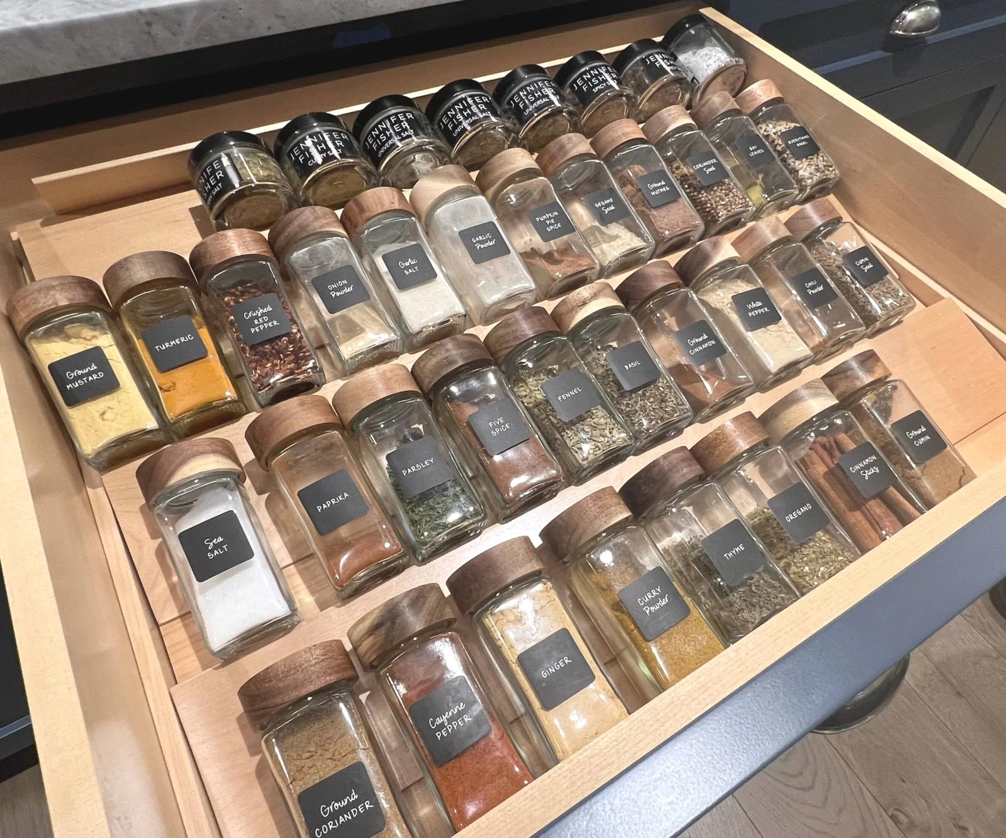 Spices organized on a rack in kitchen drawer.
