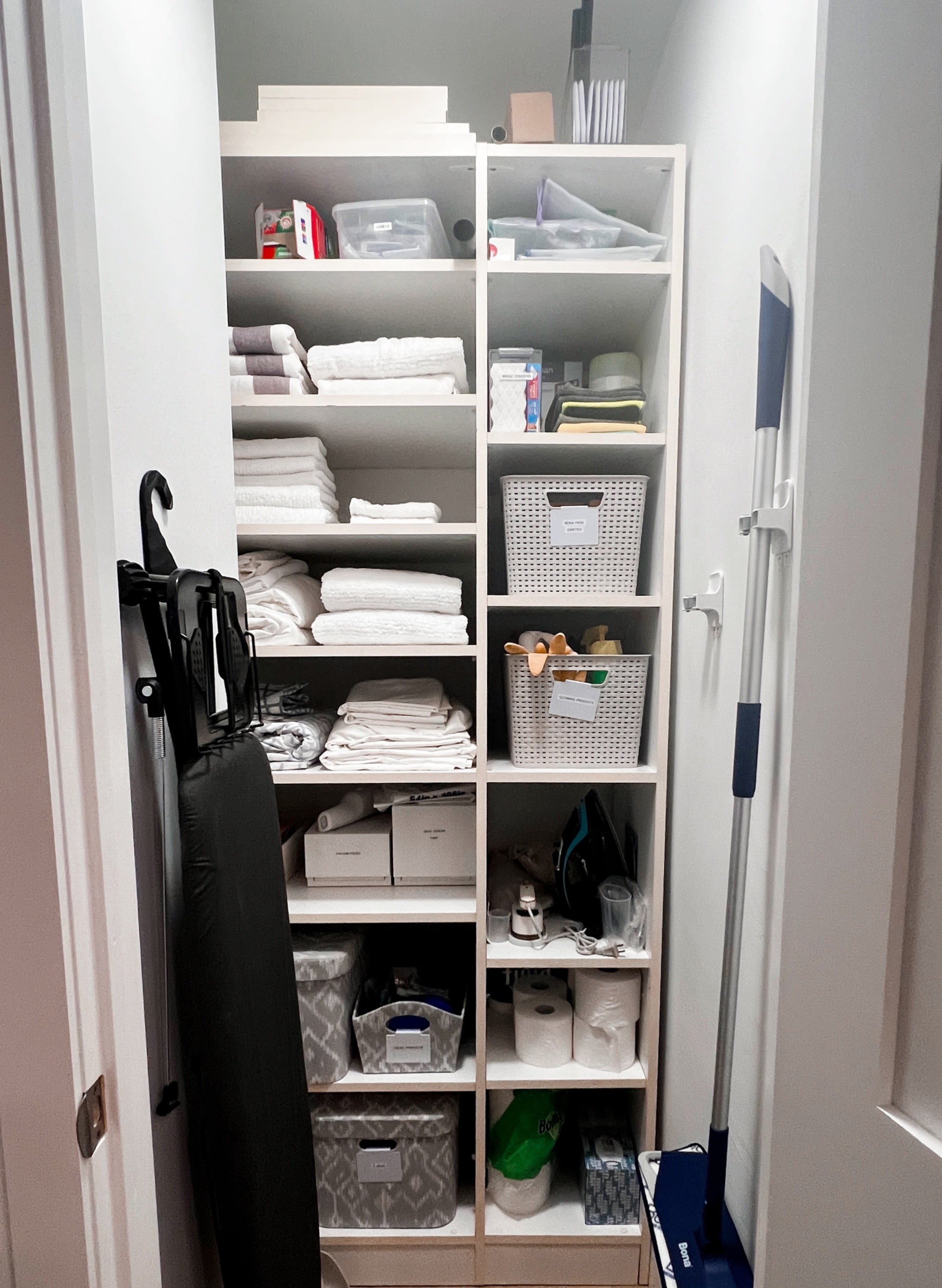Linen closet with bins and folded white towels
