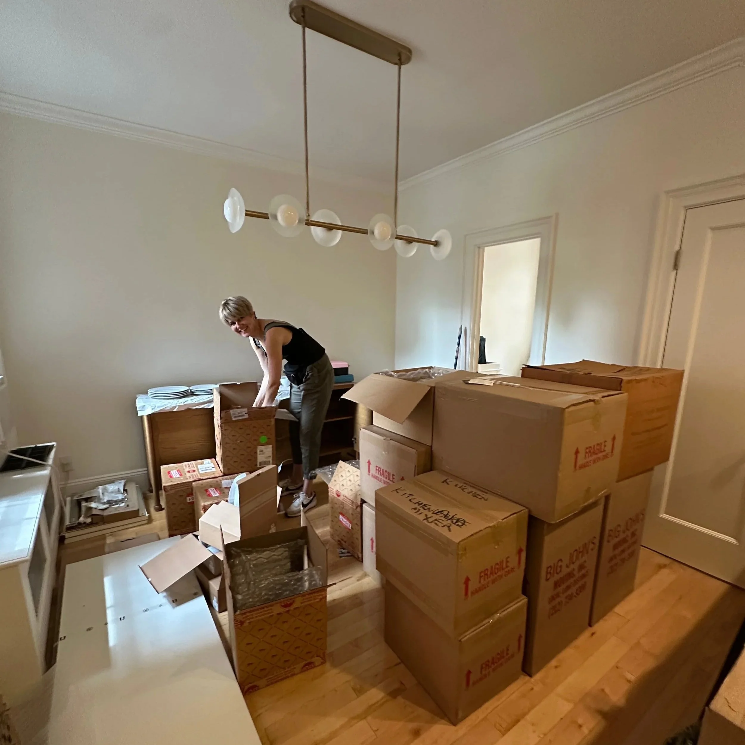 A woman smiling while unpacking moving boxes in a living room