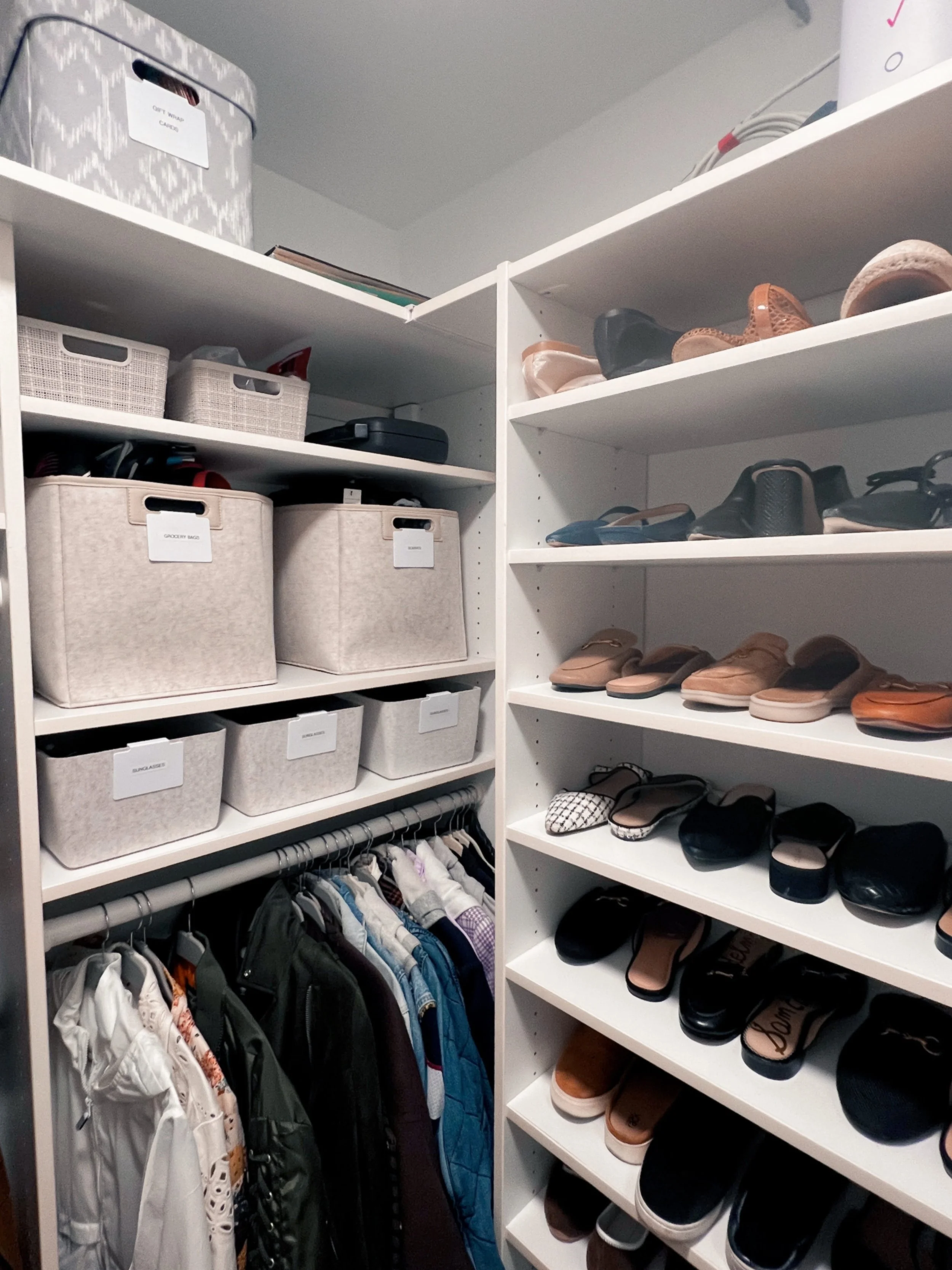A walk in closet with shoe wall and bins for organization.