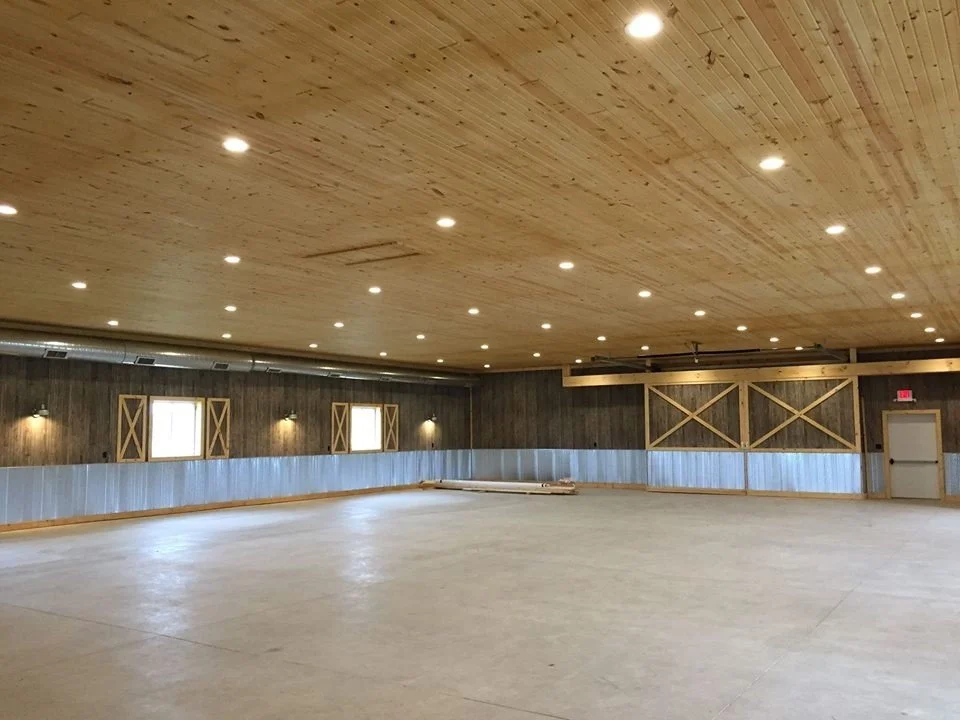Empty indoor rental venue with wooden ceiling and walls, small windows with shutters, and a smooth concrete floor rustic venue, chic venue.