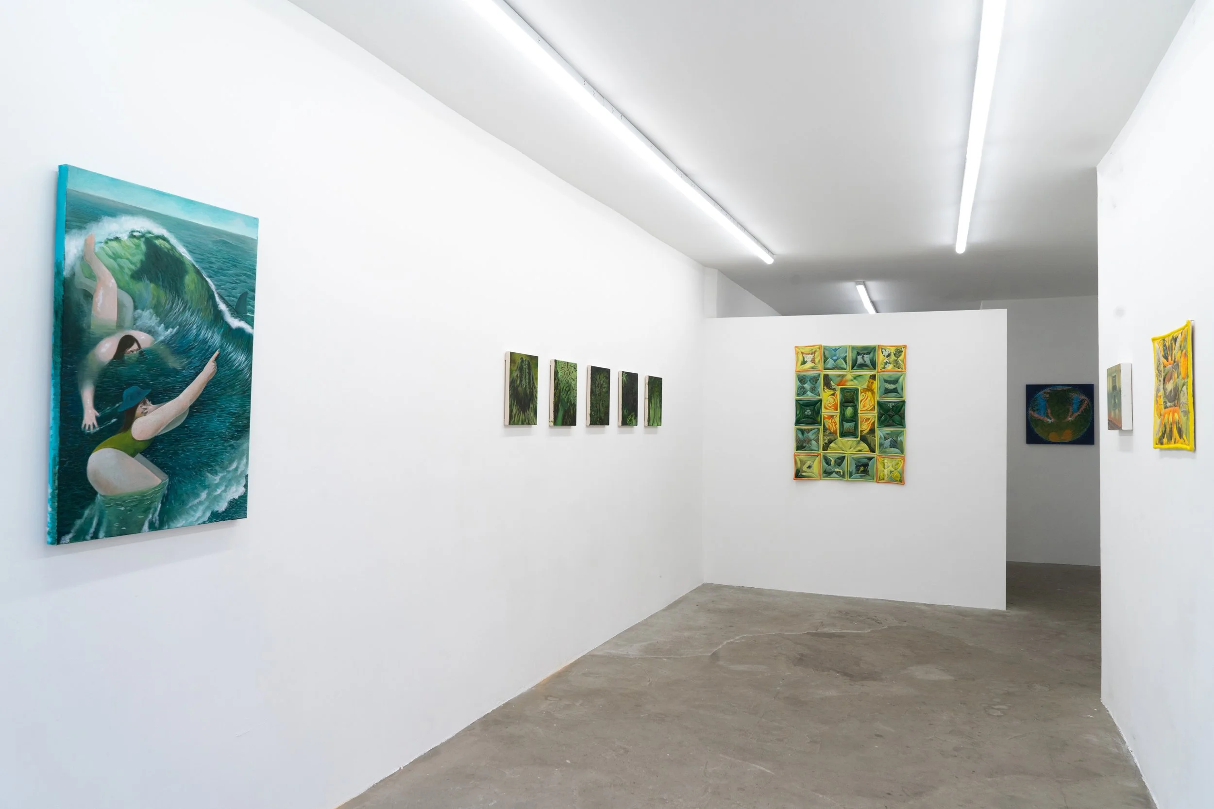 Art gallery with white walls displaying various paintings, including a large watercolor of a woman in a swimsuit with a wave, and several smaller colorful abstract and landscape artworks.