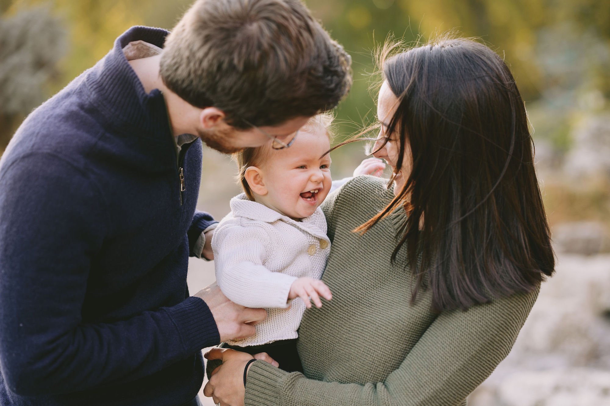 Family photo of mom and dad holding baby and smiling