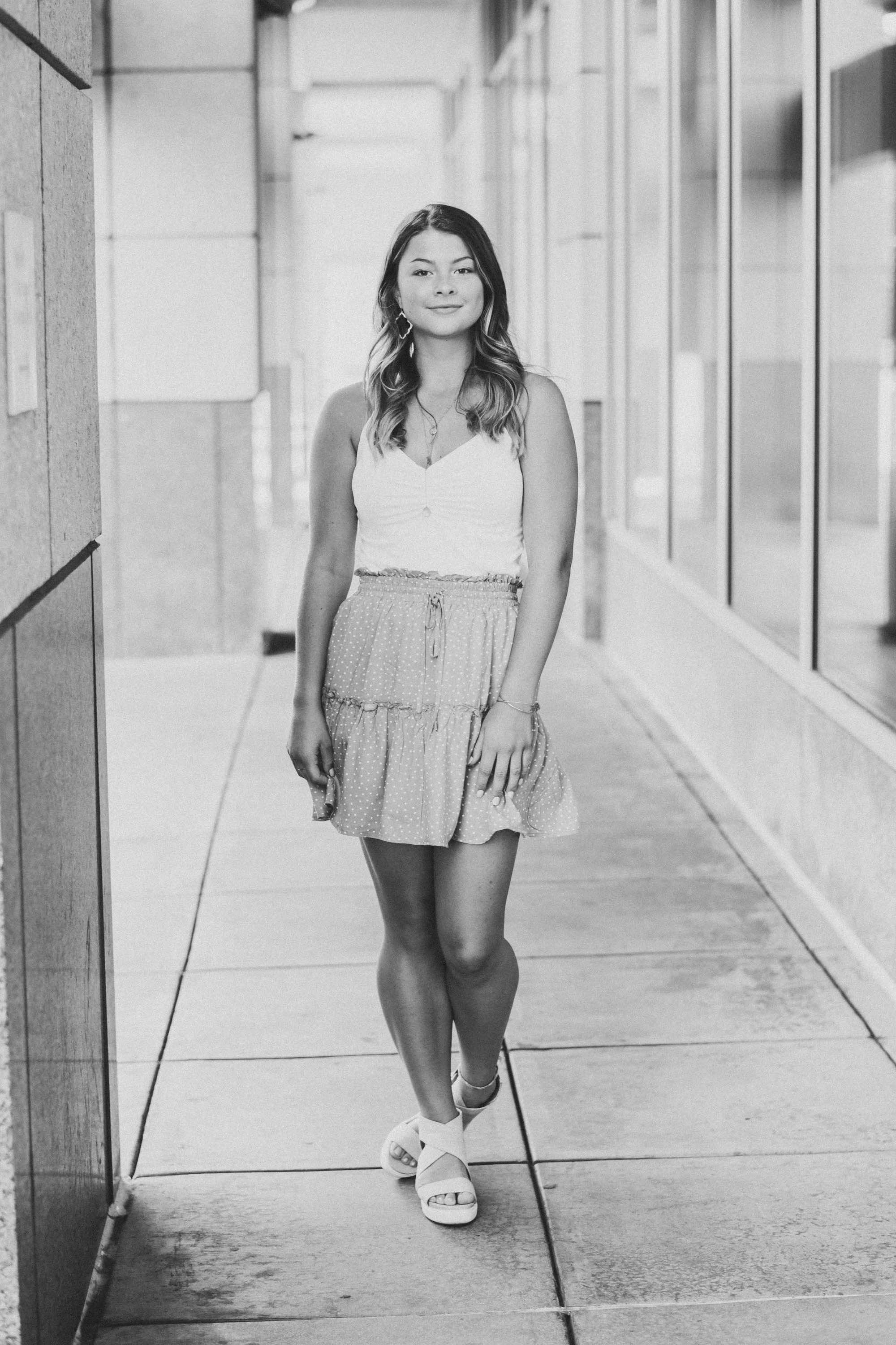 senior photo of young woman smiling on the sidewalk outside a building