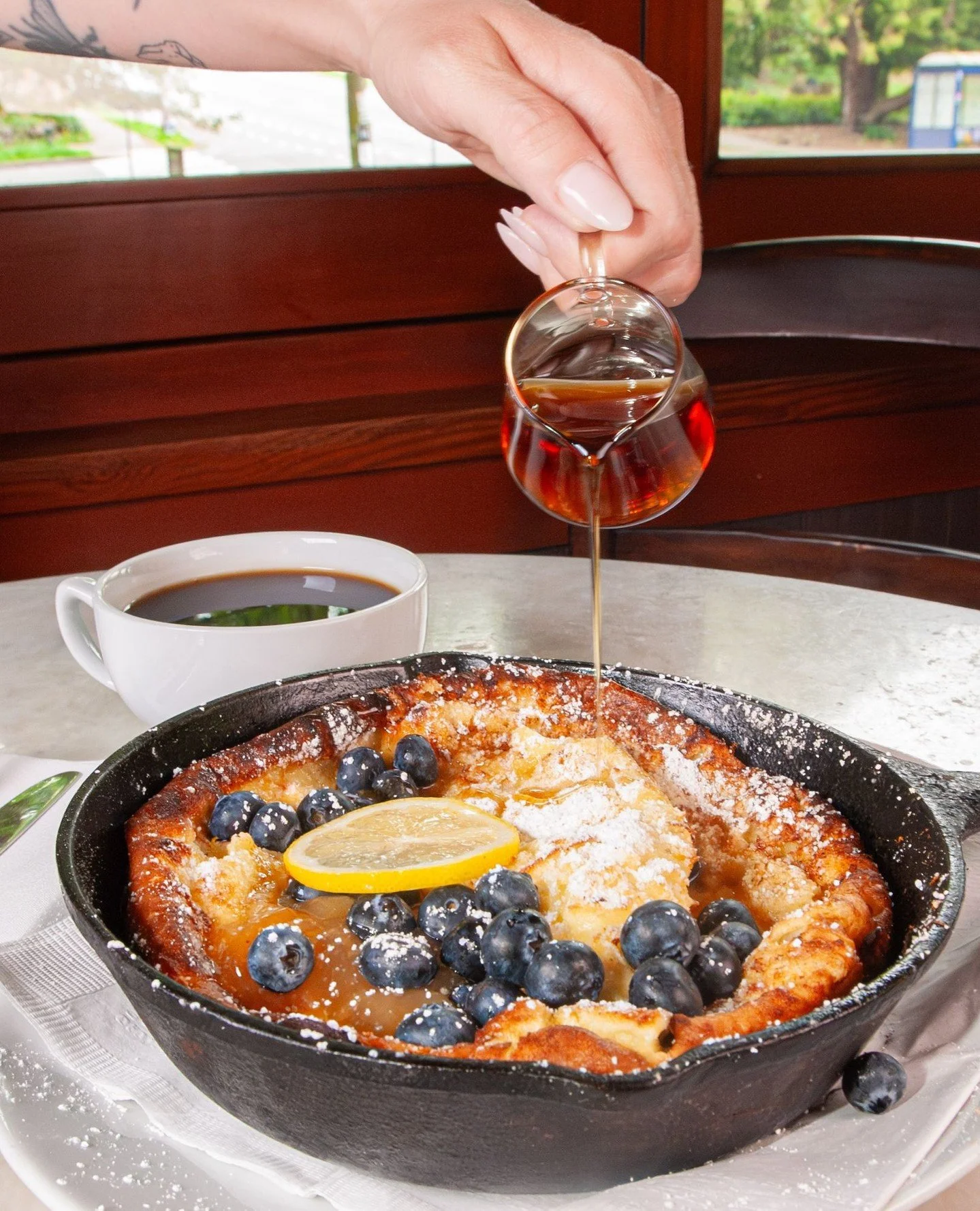We've been hard at work crafting a satisfyingly sweet, vegetarian addition to our daily brunch menu - our new Dutch Baby! ⁠
⁠
Topped with fresh blueberries, lemon curd, powdered sugar, and maple syrup, this oven-baked pancake puffs up like a popover 