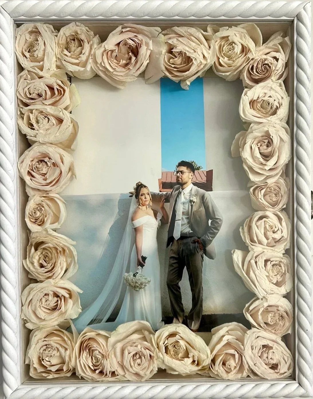 11x14 white braided wooden shadow box featuring 2 dozen chamber dried white roses and 8x10 photo of bride and groom.