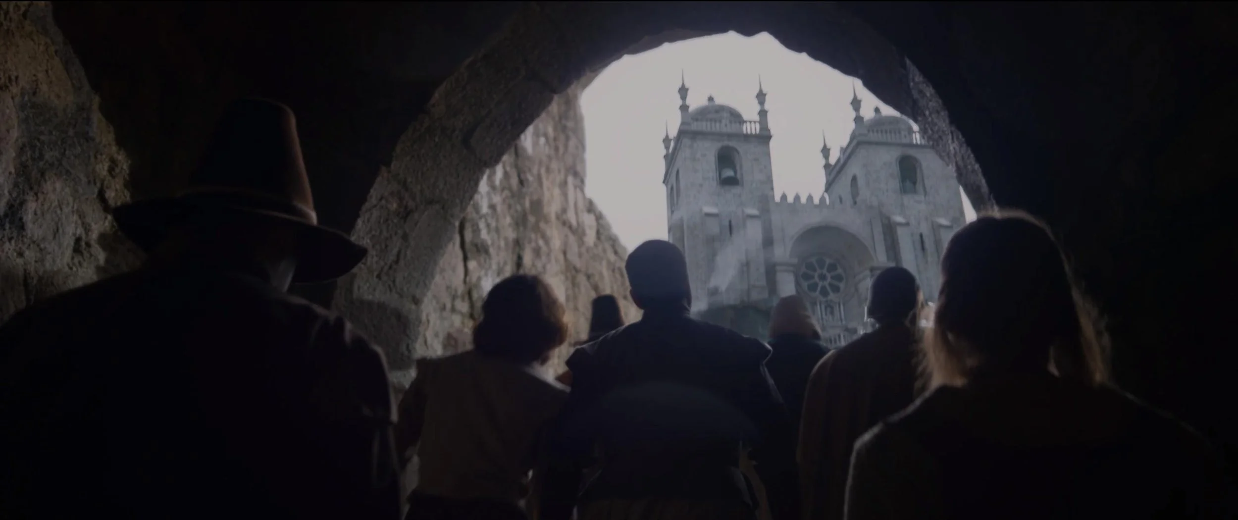 People viewing a cathedral from inside a dark tunnel.