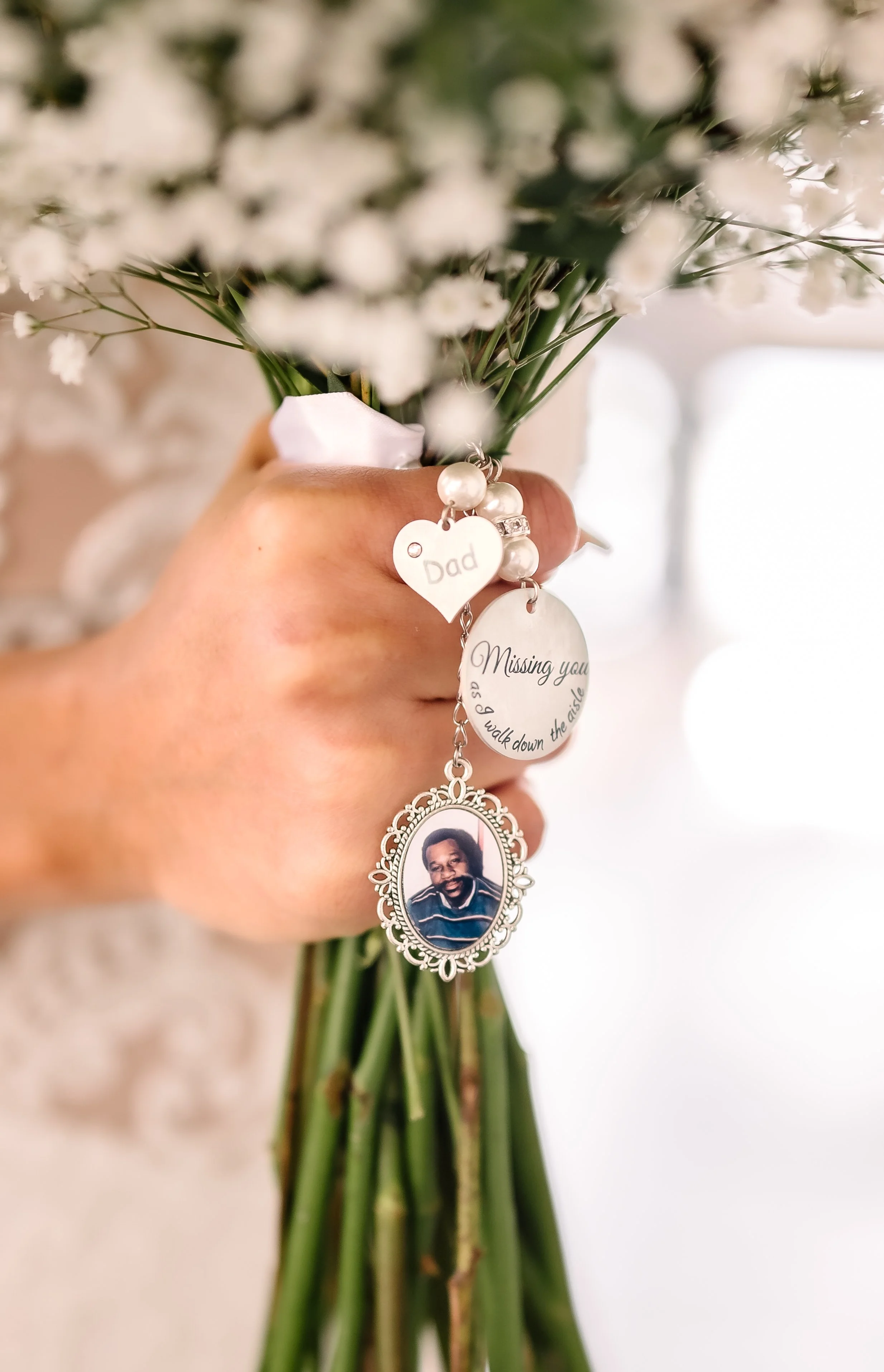 Hand holding a bouquet on flowers with wedding trinkets.