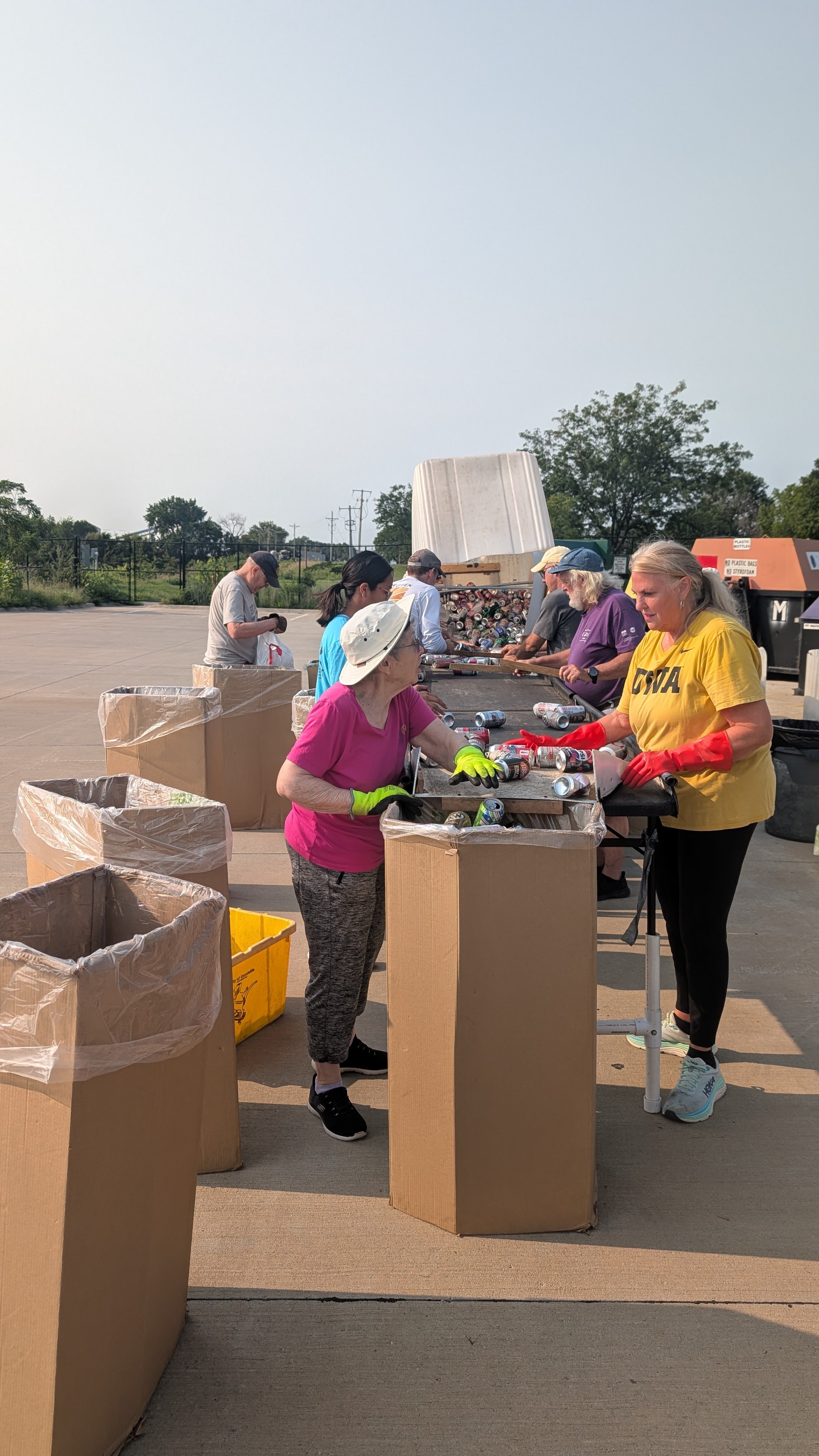 Rotarian sort donated cans into bags across a high work table