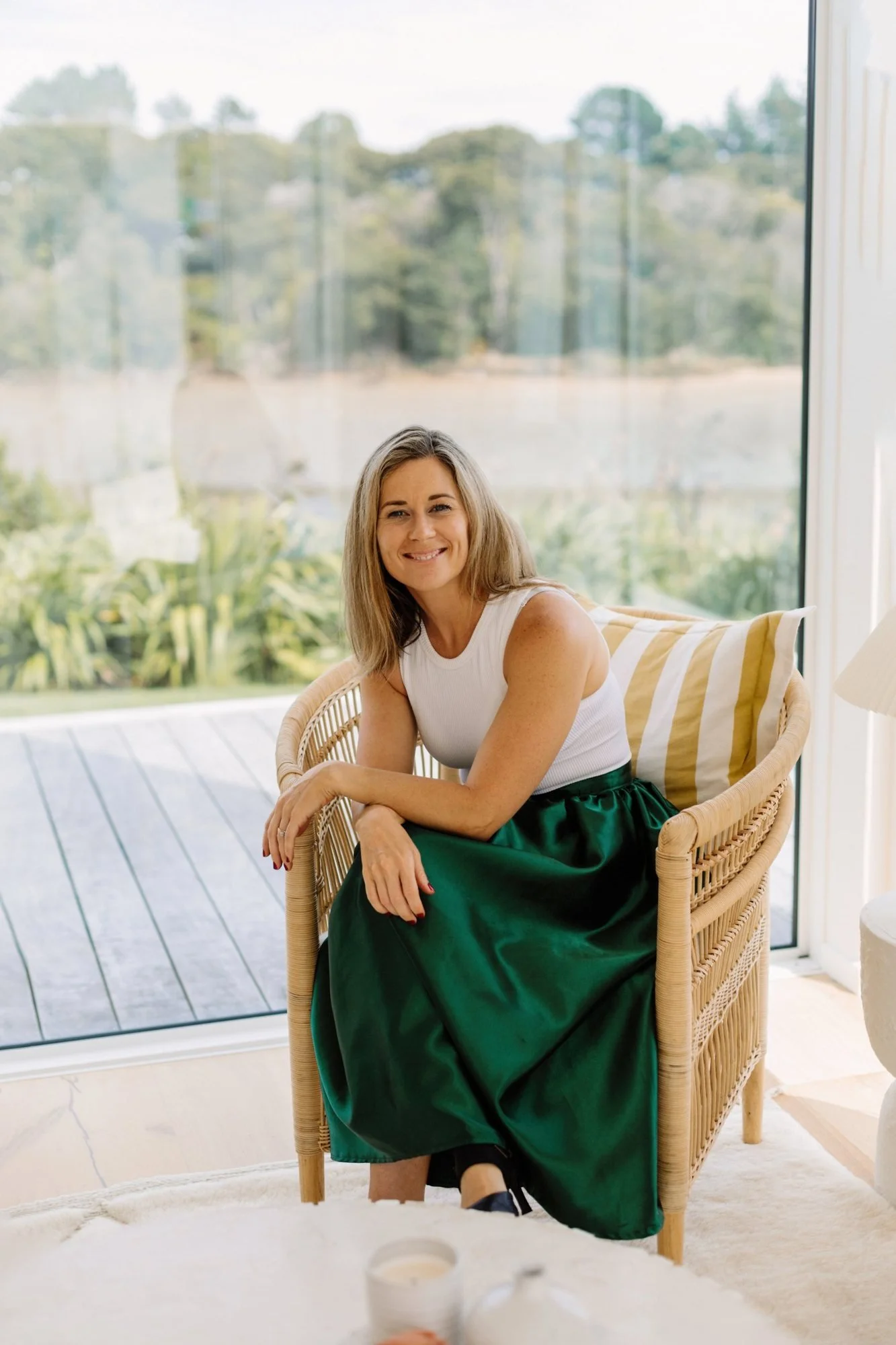 Kirstie Vesseur in a green skirt, seated in a rattan chair