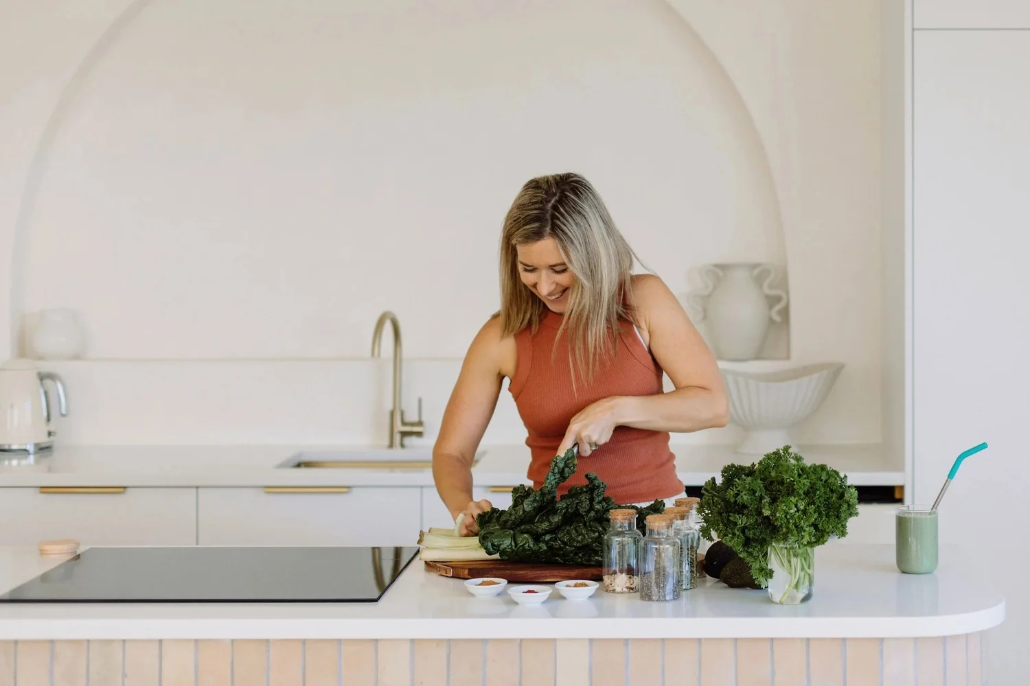 Kirstie smiling in her kitchen, chopping silverbeet