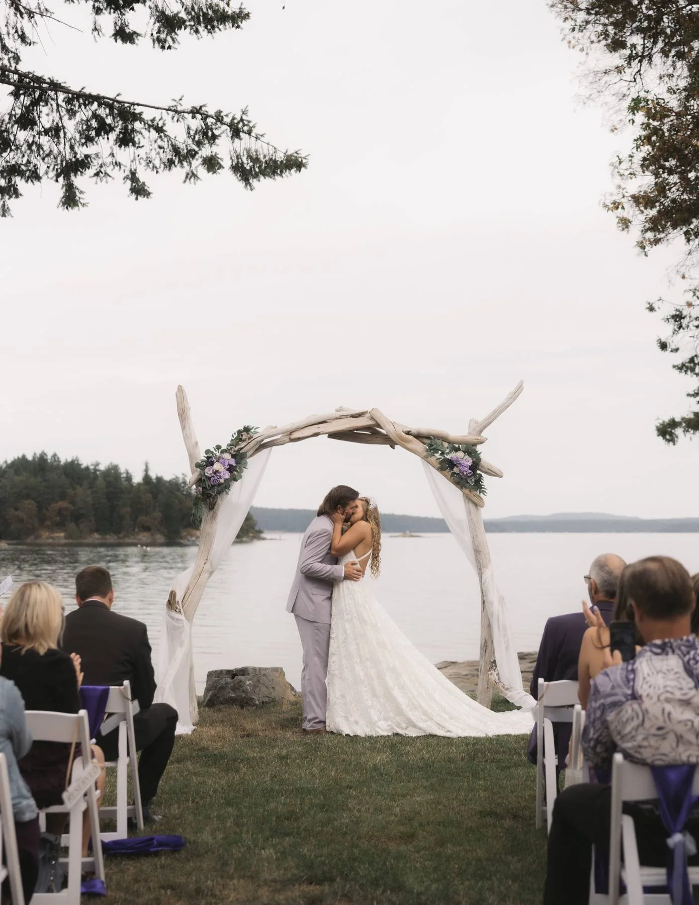 Bride and groom sharing their first kiss during an oceanfront wedding ceremony near Parksville on Vancouver Island
