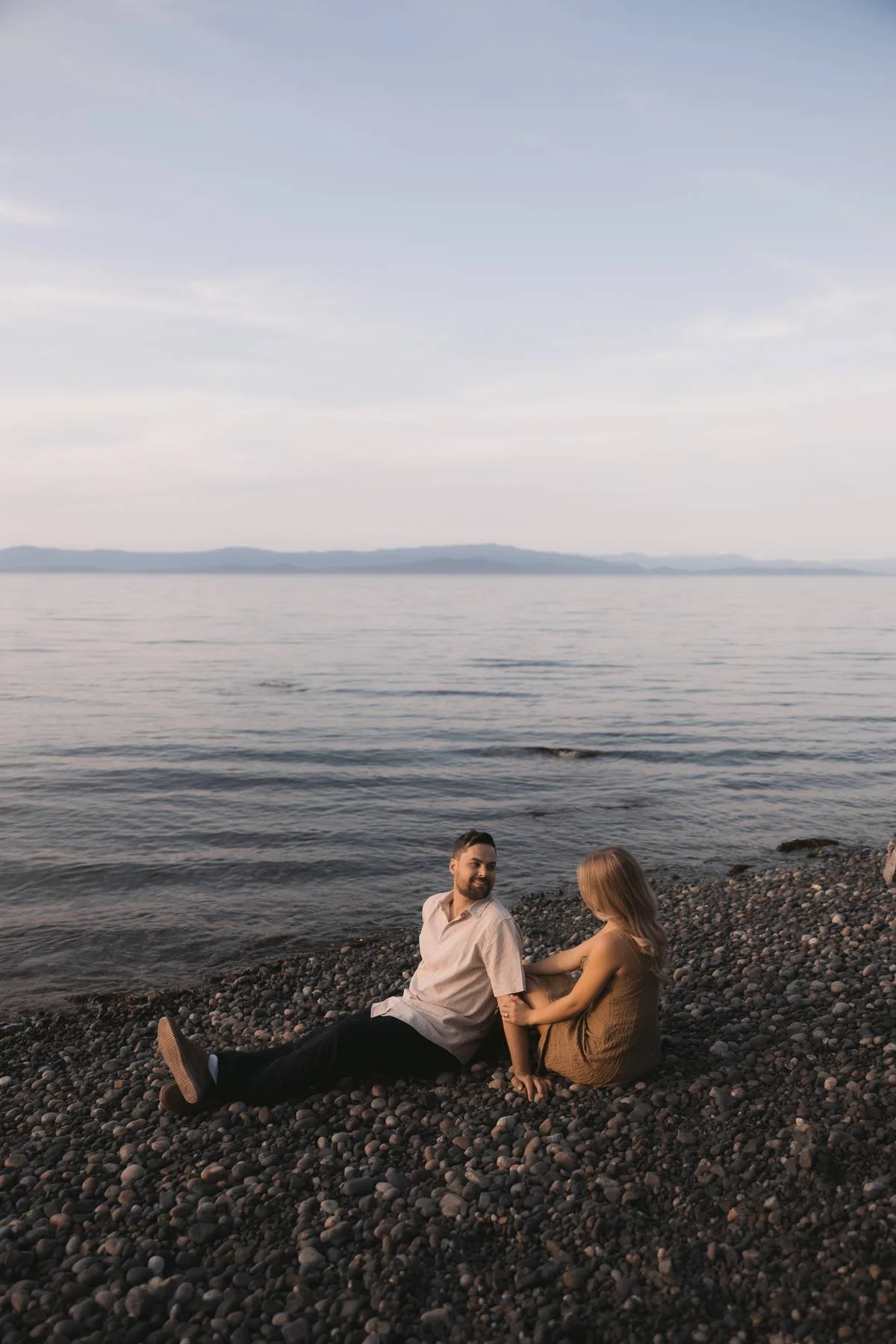 Couple sitting together on a rocky beach at sunset near Parksville on Vancouver Island