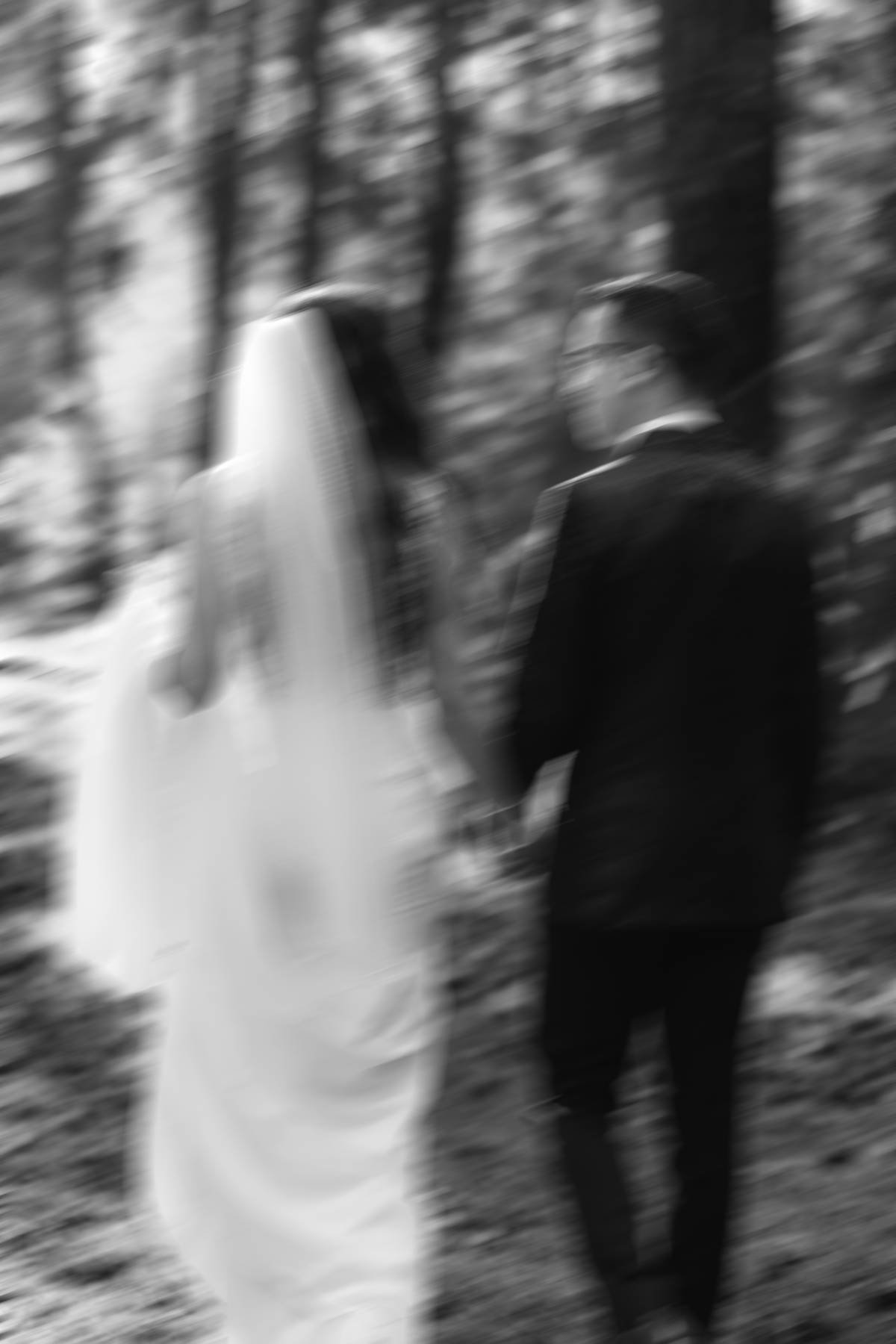 Artistic motion blur wedding portrait of couple walking through forest in Parksville