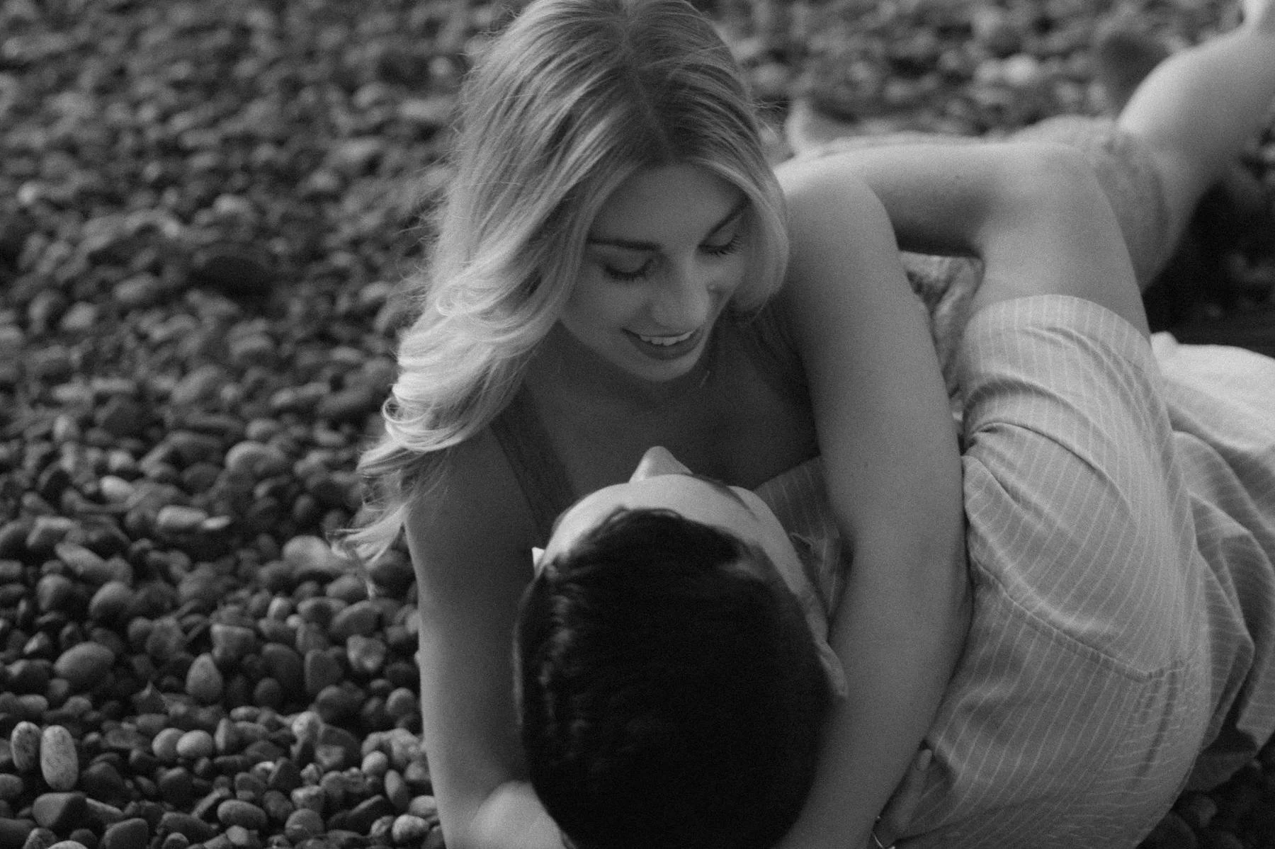 Couple lying on rocky beach during engagement session near Parksville, Vancouver Island, candid romantic moment