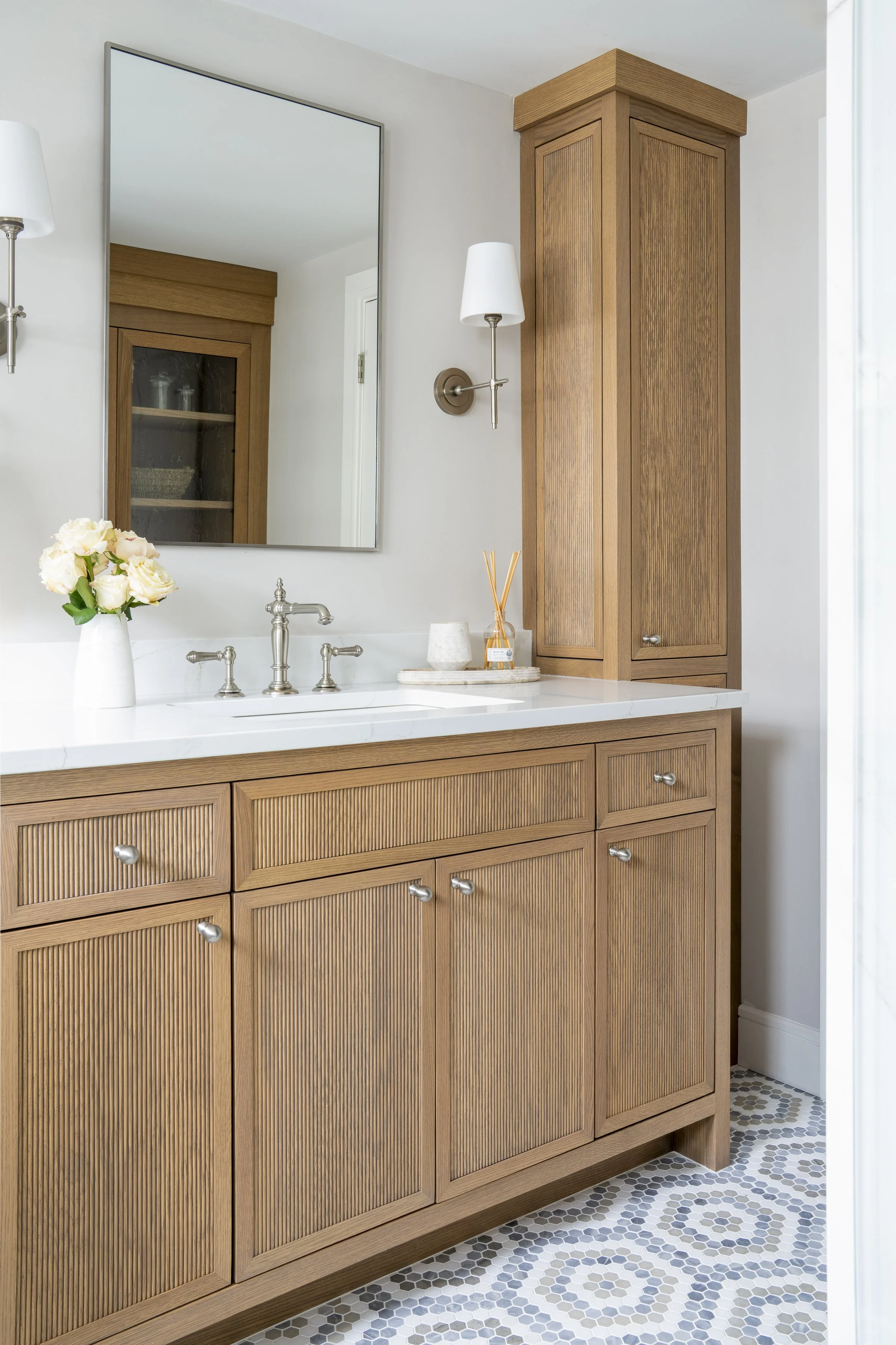 Custom reeded wood bathroom vanity with marble countertop and warm wood cabinetry by Blakely Interior Design.