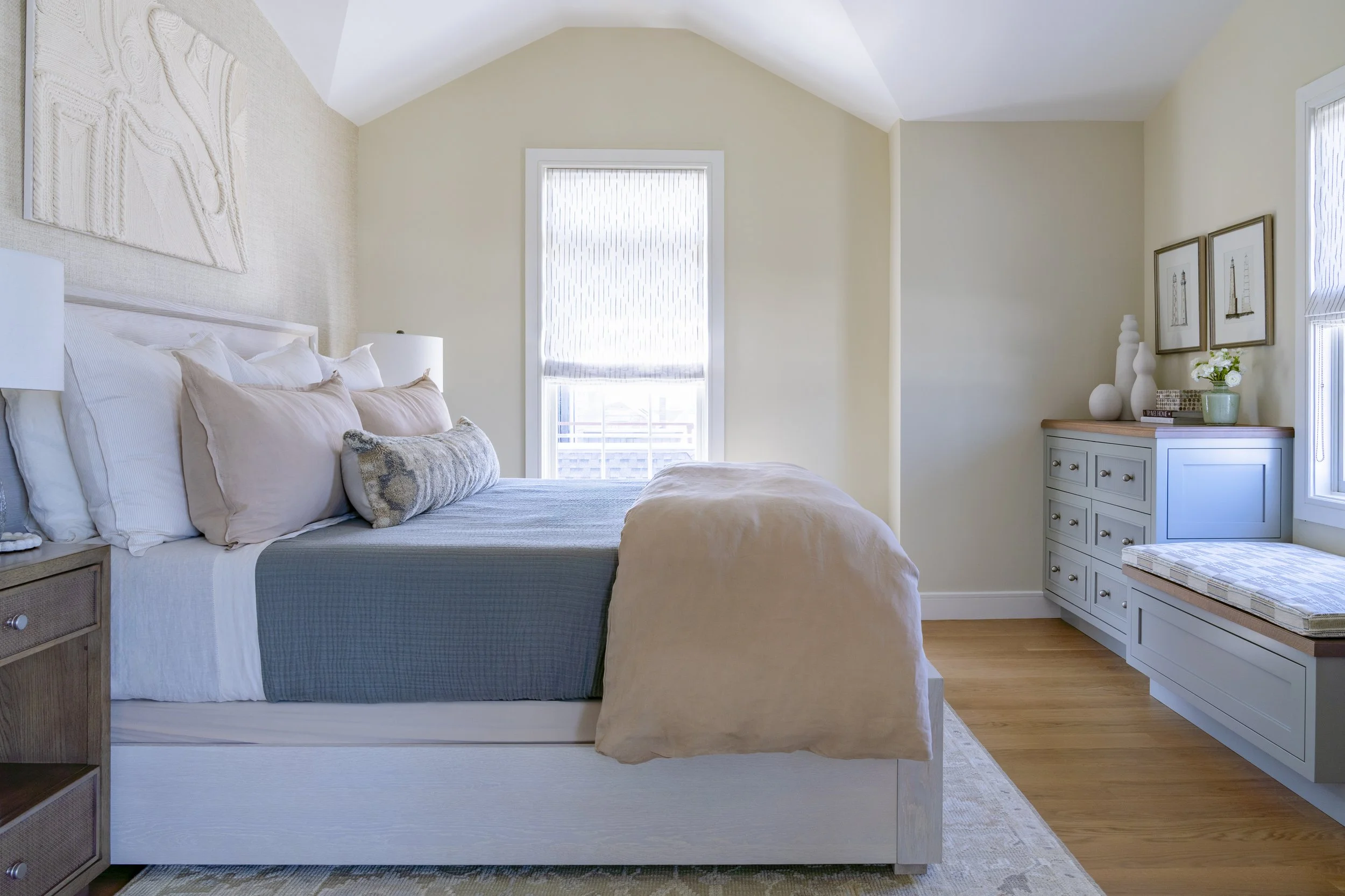 Soft blue bedroom with layered bedding and natural wood furnishings in the Jerusalem Heights beach house in Narragansett, Rhode Island.