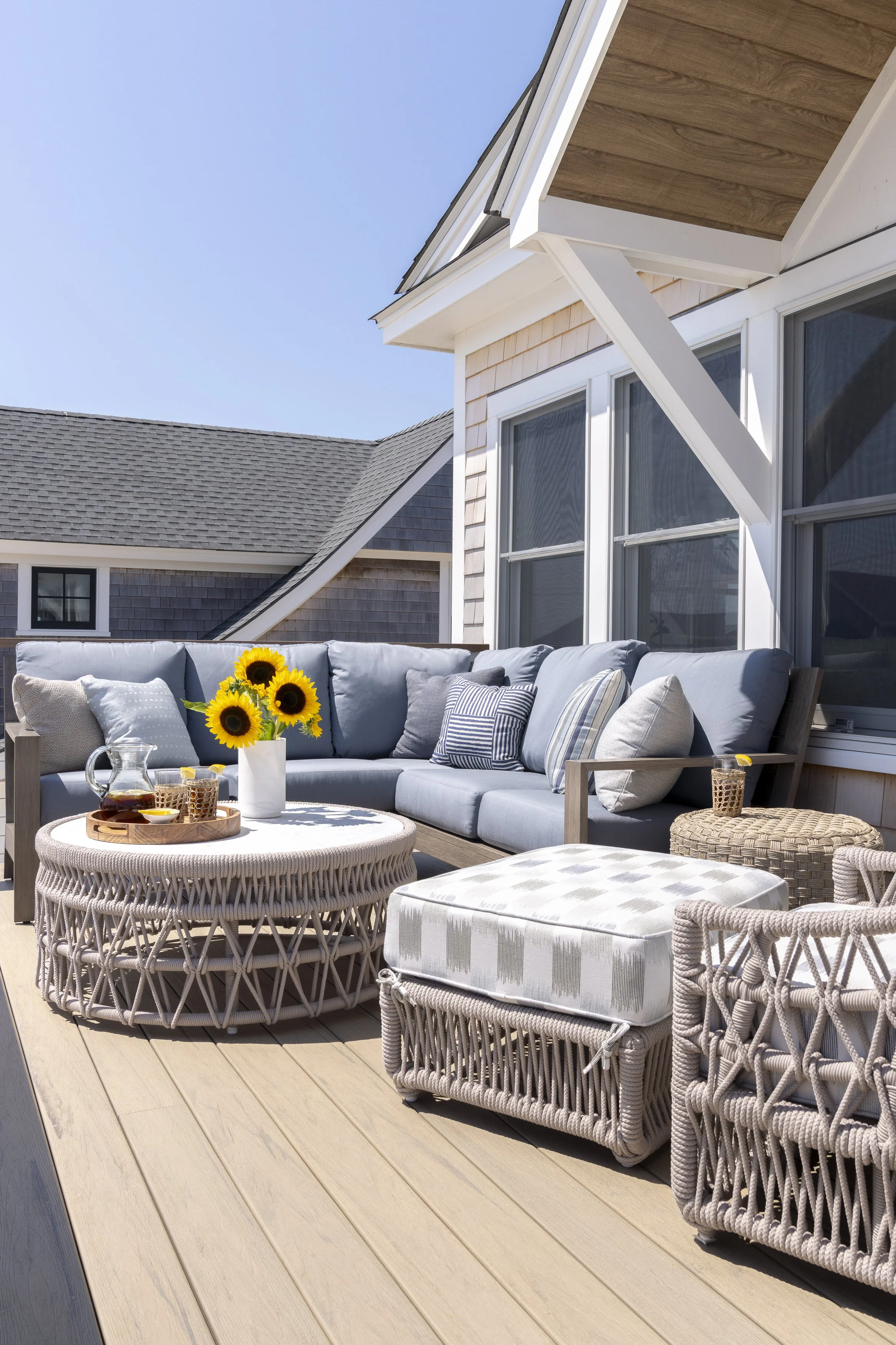Outdoor lounge deck with woven furniture and coastal views at a Narragansett, Rhode Island beach house.