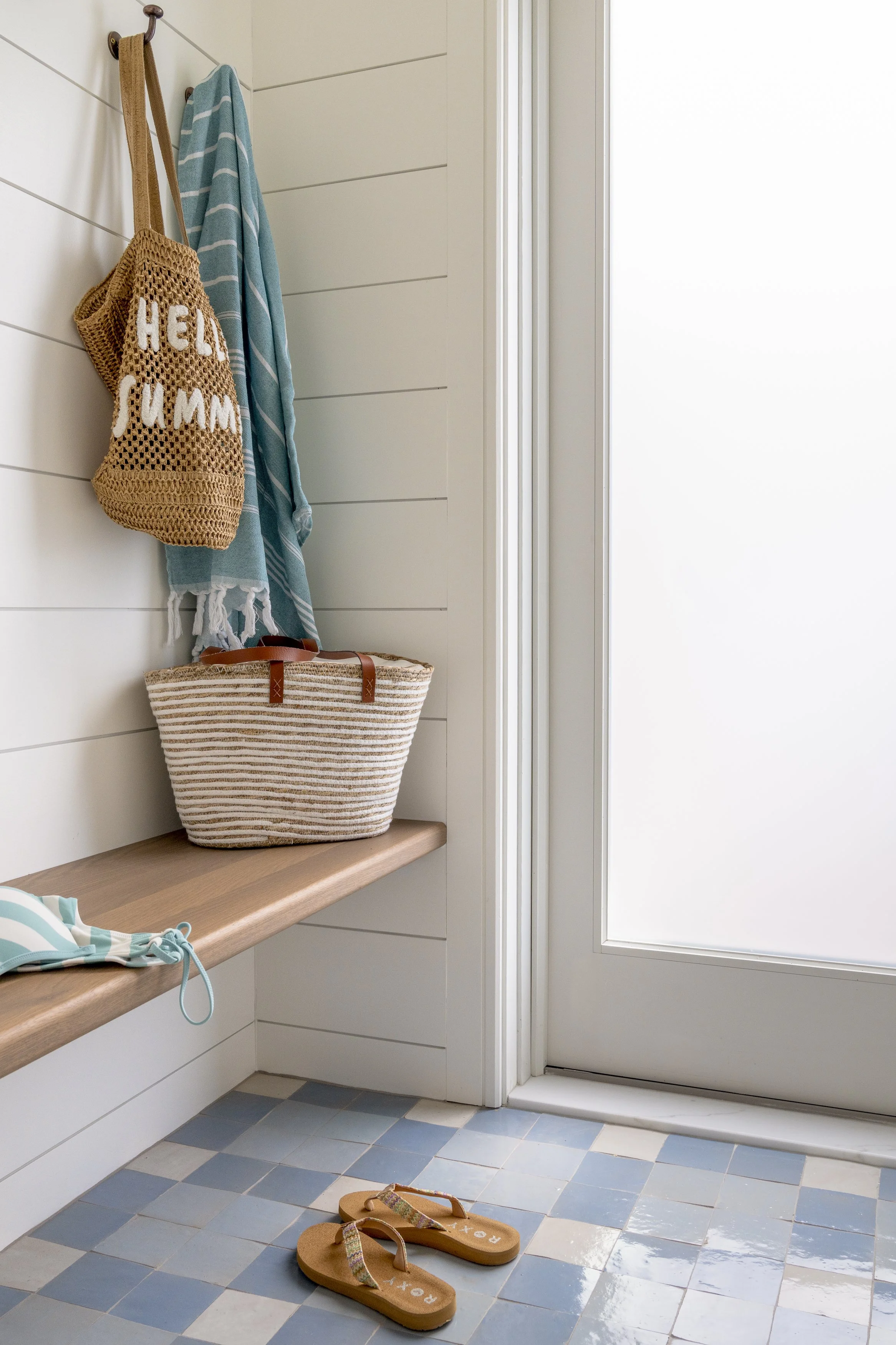 Beach house mudroom with built-in bench, woven baskets and coastal accessories in Narragansett, Rhode Island.